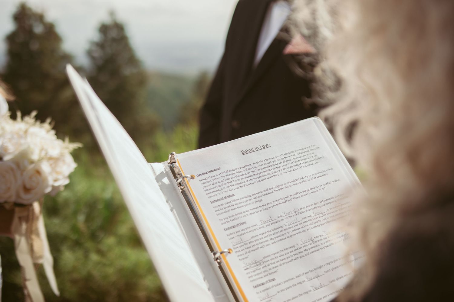 Wedding ceremony documents and papers being read outdoors.