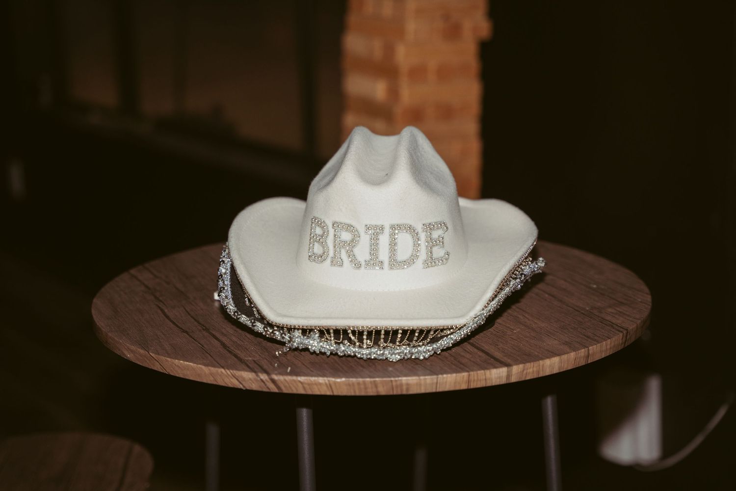 Two cowboy hats labeled for bride and groom sit on a wooden surface.