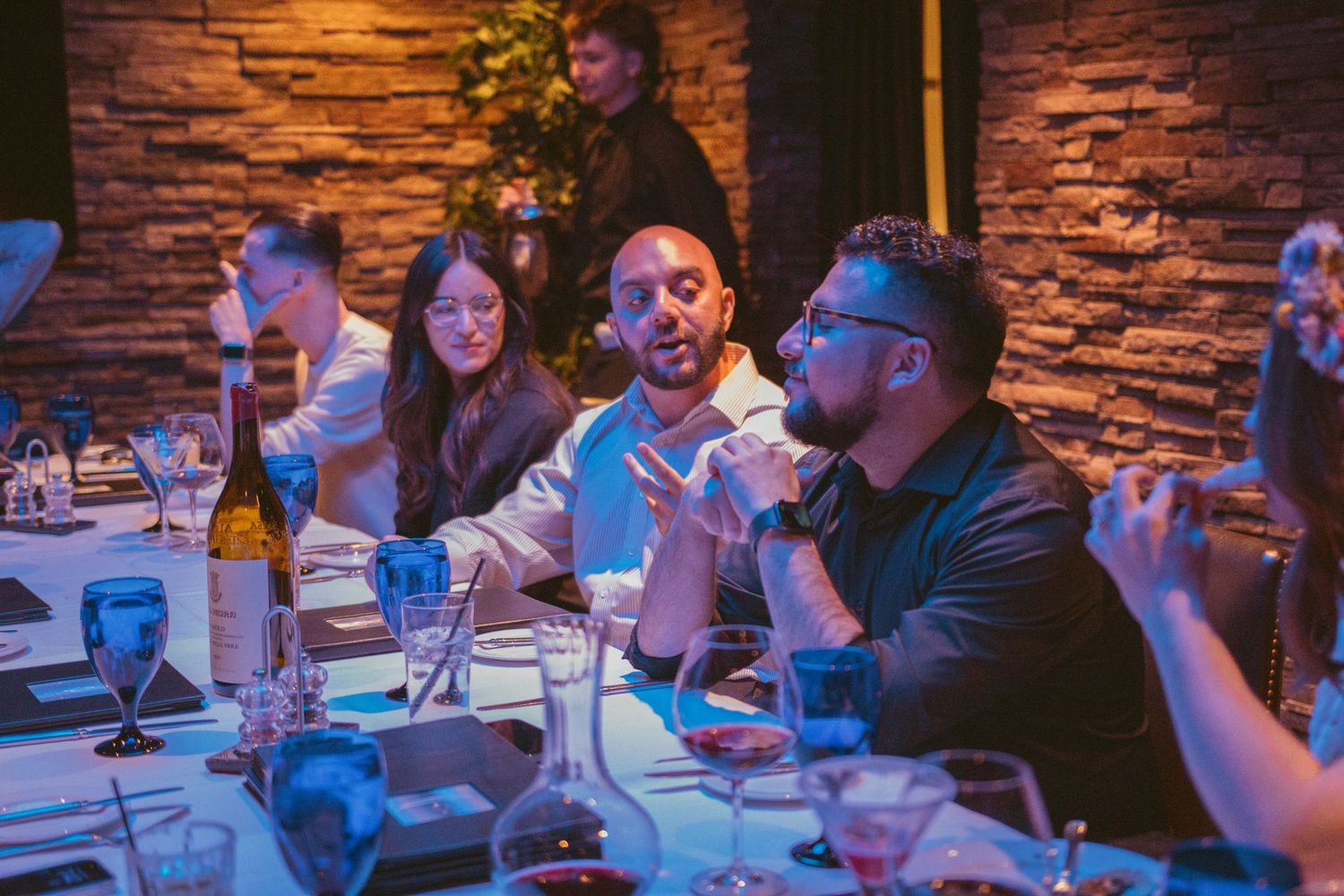 Wedding guests seated at tables in a rustic venue with ambient lighting.