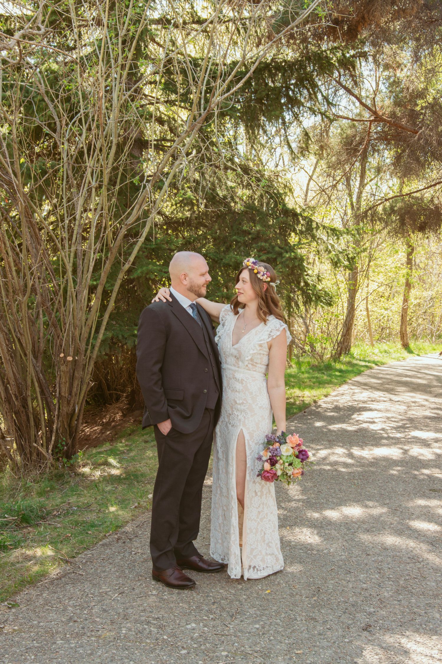 A couple shares a romantic moment on a garden path surrounded by spring greenery.
