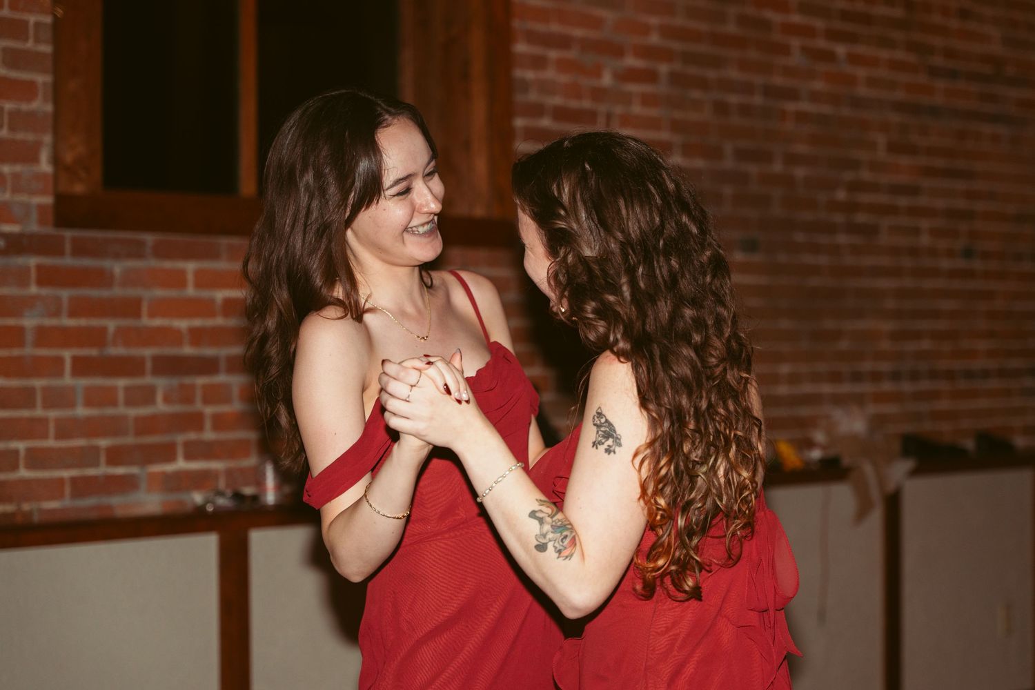 Couples dancing together at a wedding reception in a rustic brick venue.