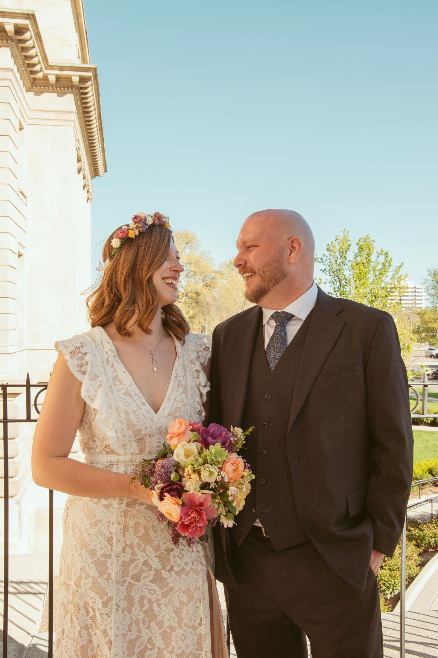 Couple in wedding attire sharing intimate moments against an architectural backdrop.
