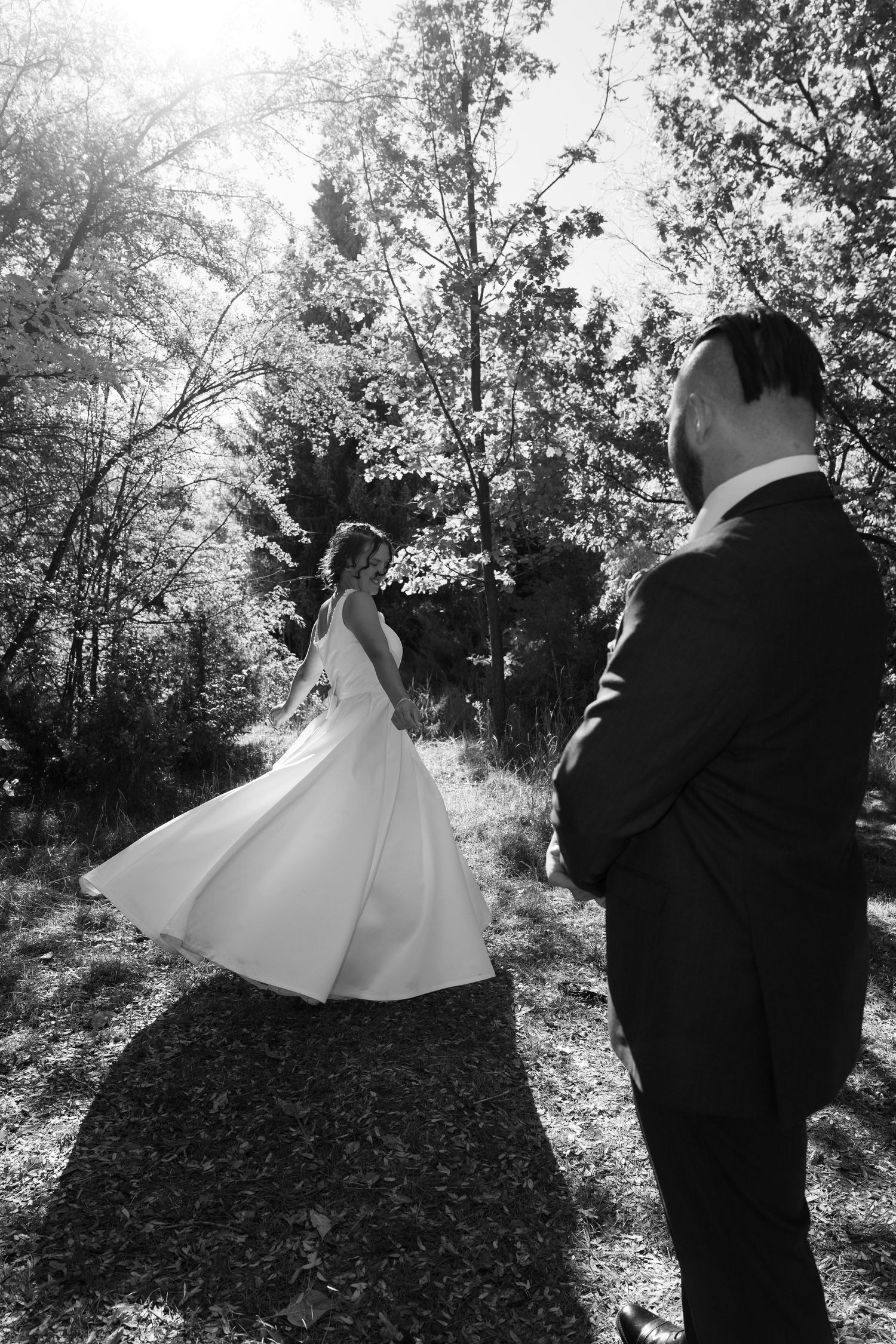 Black and white silhouette of wedding couple dancing in wooded setting.