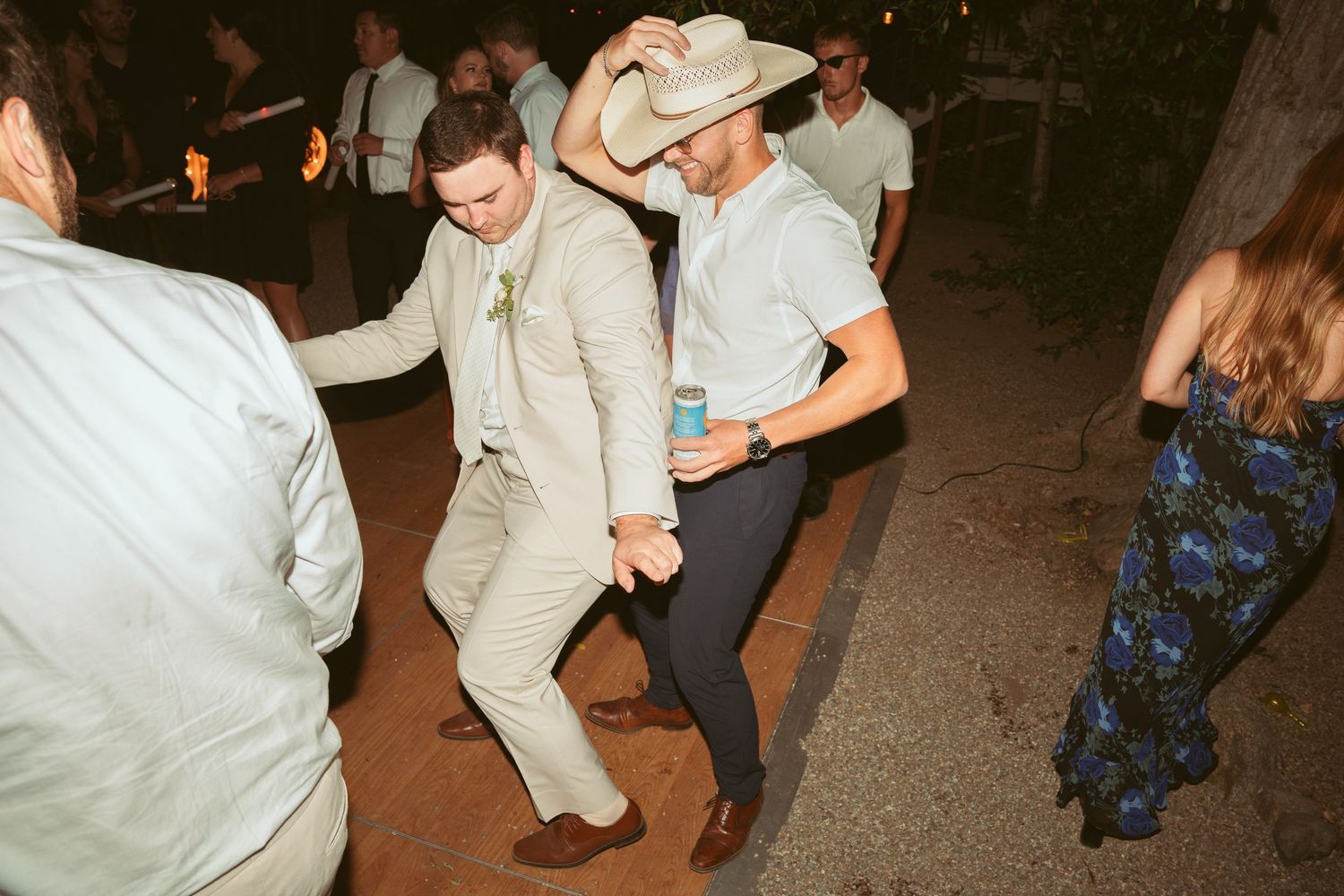 Guests dancing and having fun at a lively wedding reception with one person wearing a light colored suit.