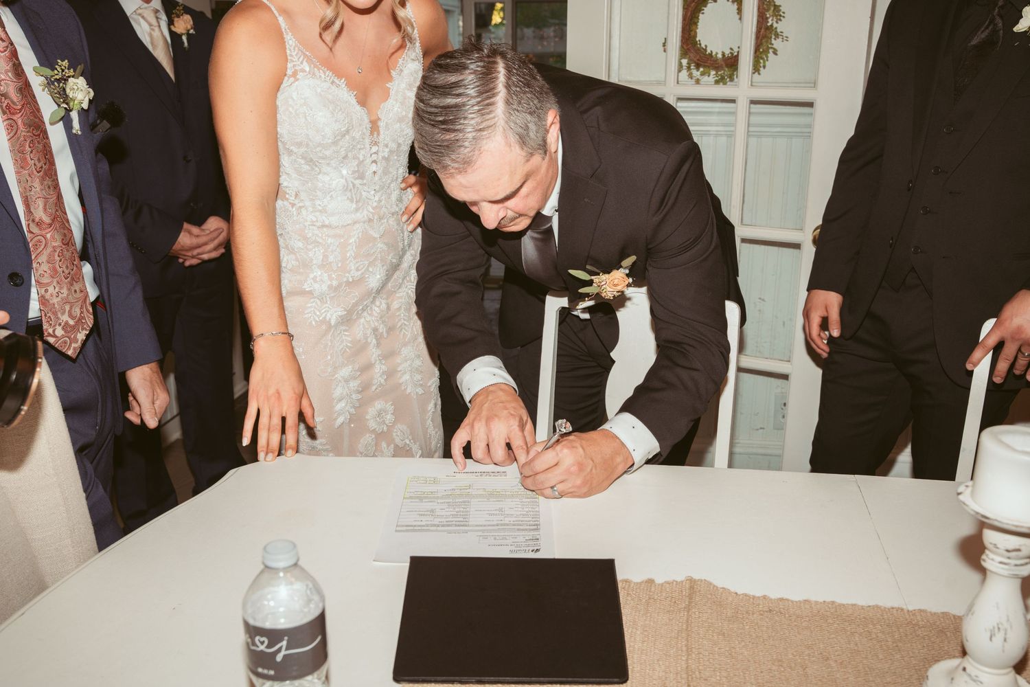 Wedding party dancing and celebrating in a white-walled reception venue.