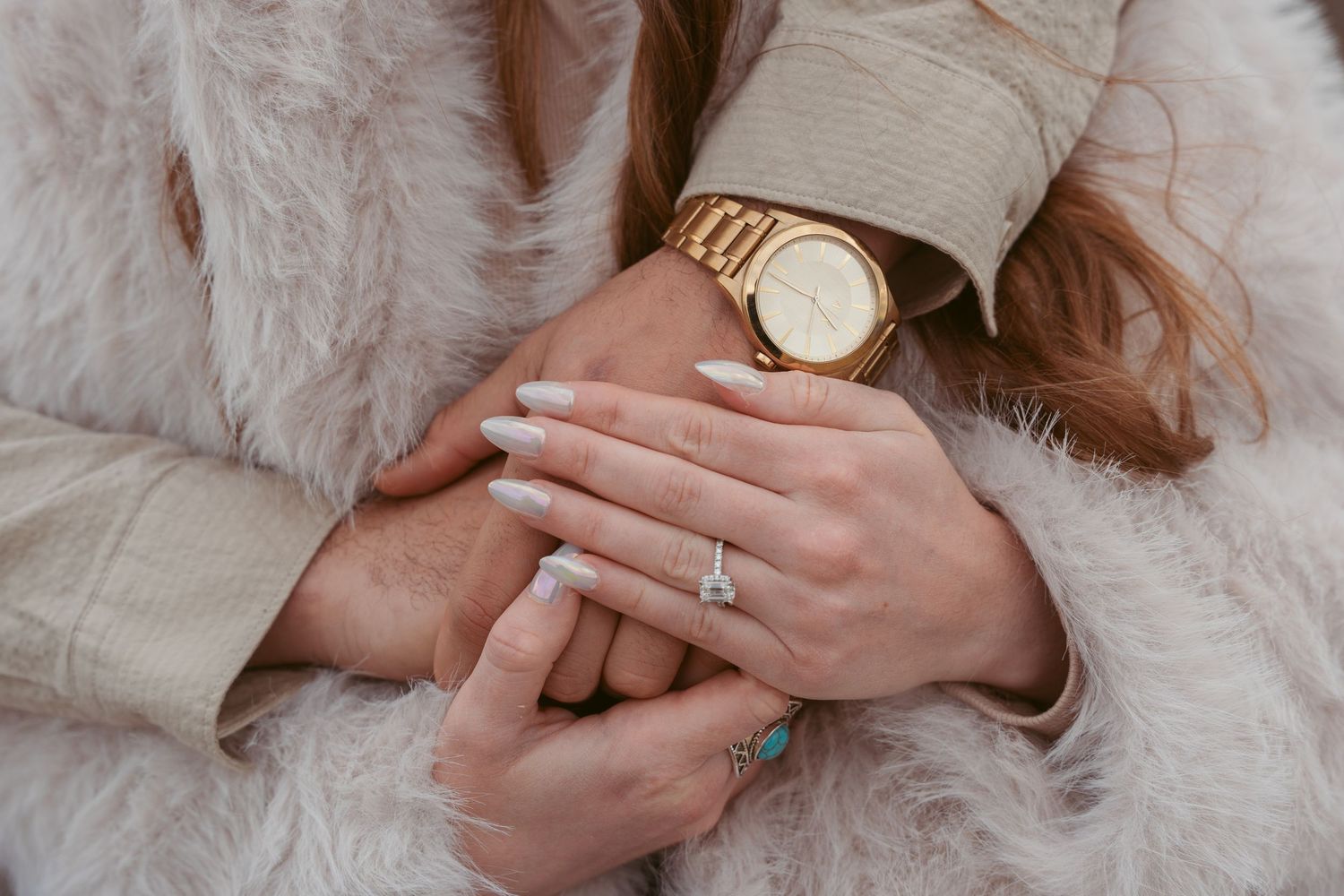 Close up shot of hands with engagement ring in a romantic setting.