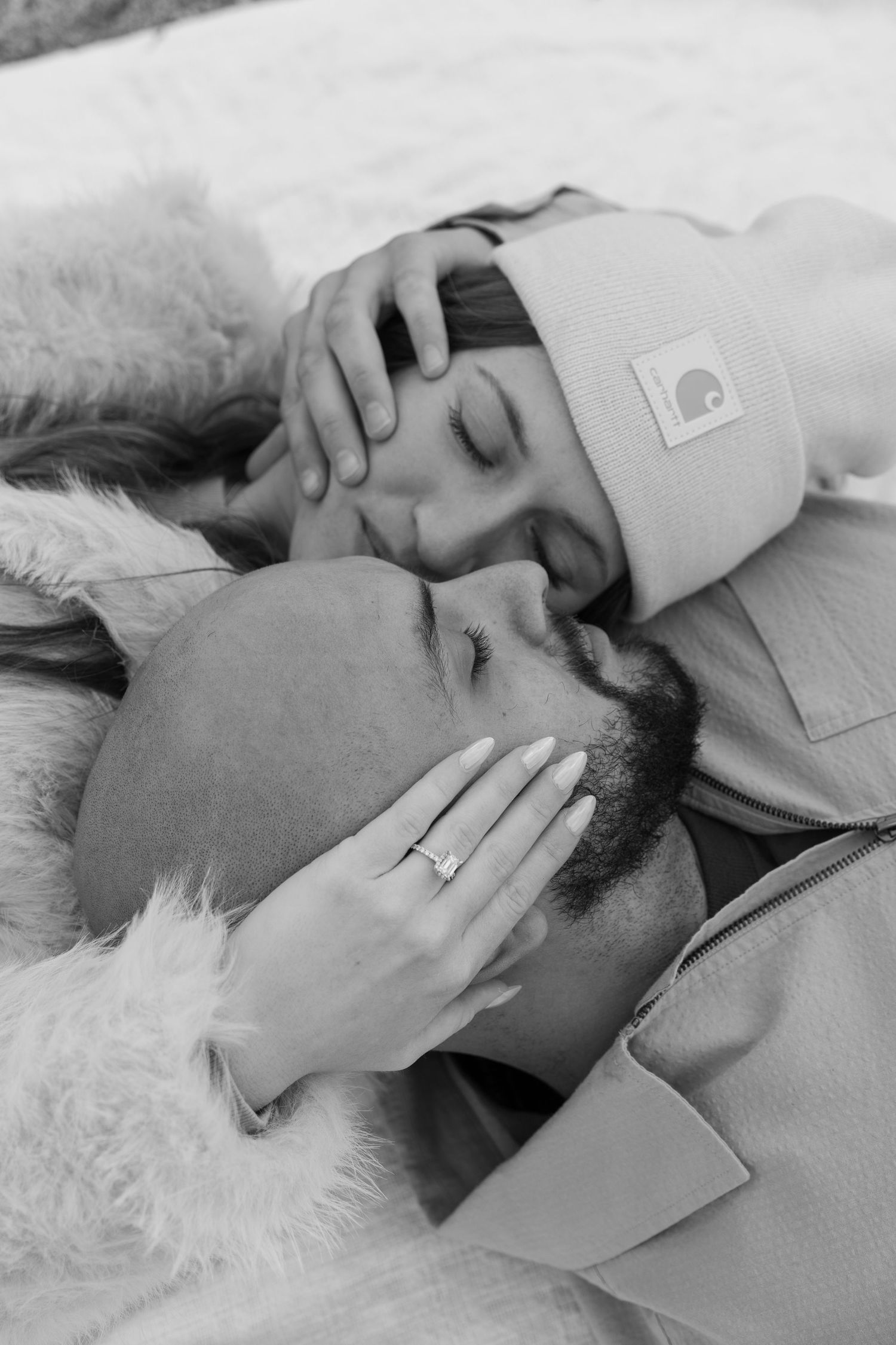 An intimate black and white portrait of a couple lying together.