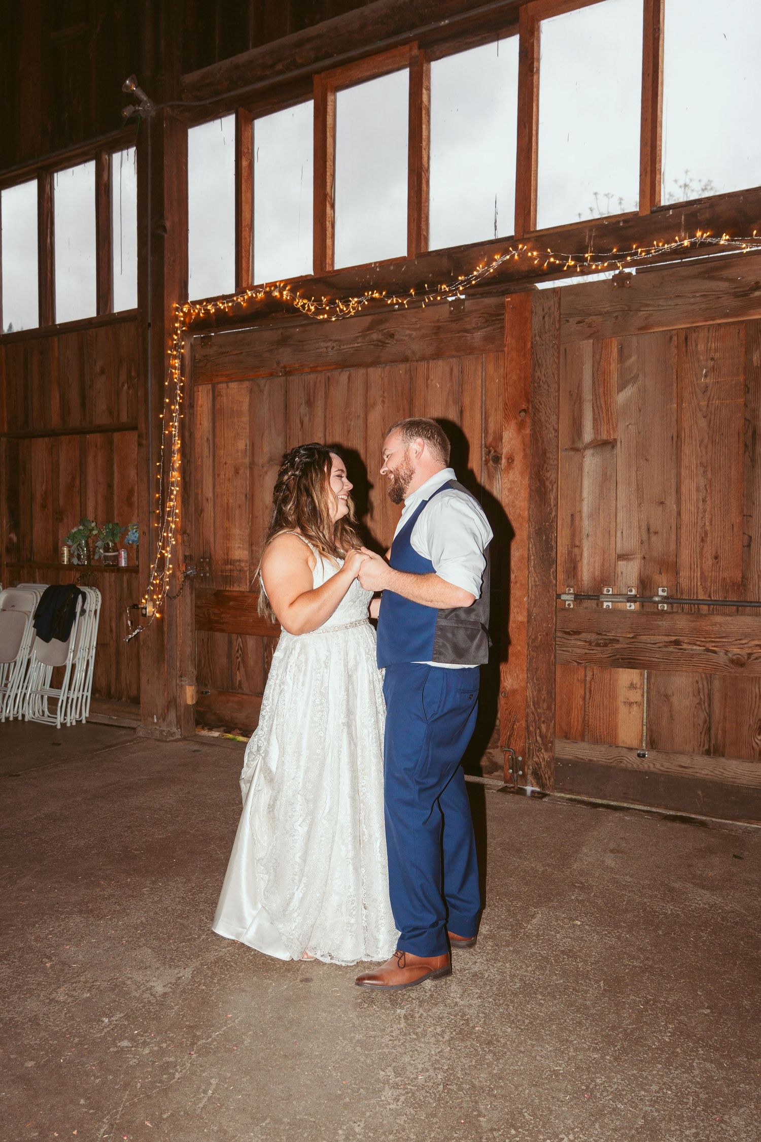 A romantic dance moment captured in a rustic wooden barn setting.