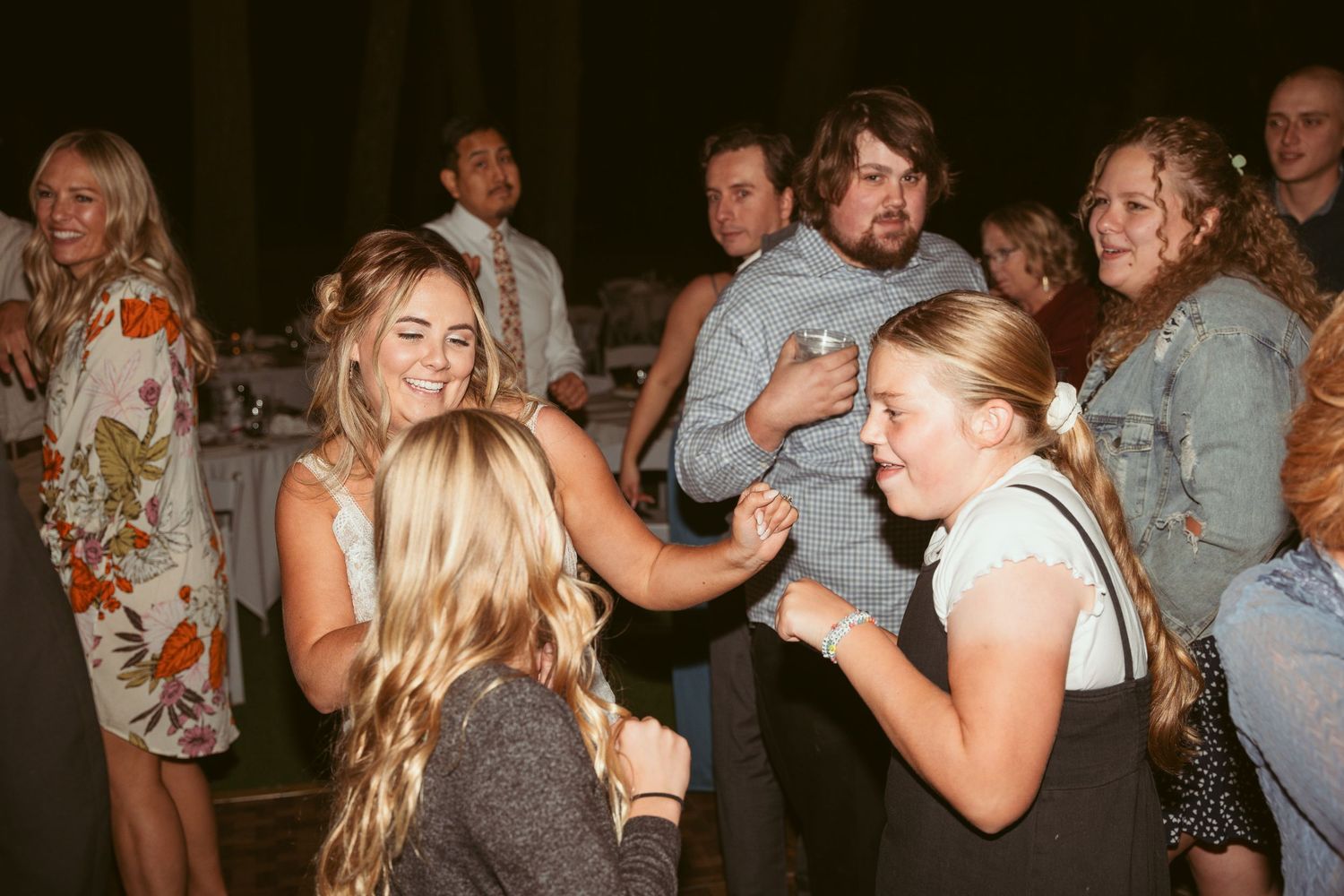Wedding guests enjoying themselves on a dimly lit dance floor during an evening celebration.