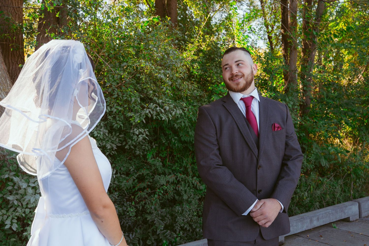 A couple shares their first look moment on their wedding day in a forest setting.