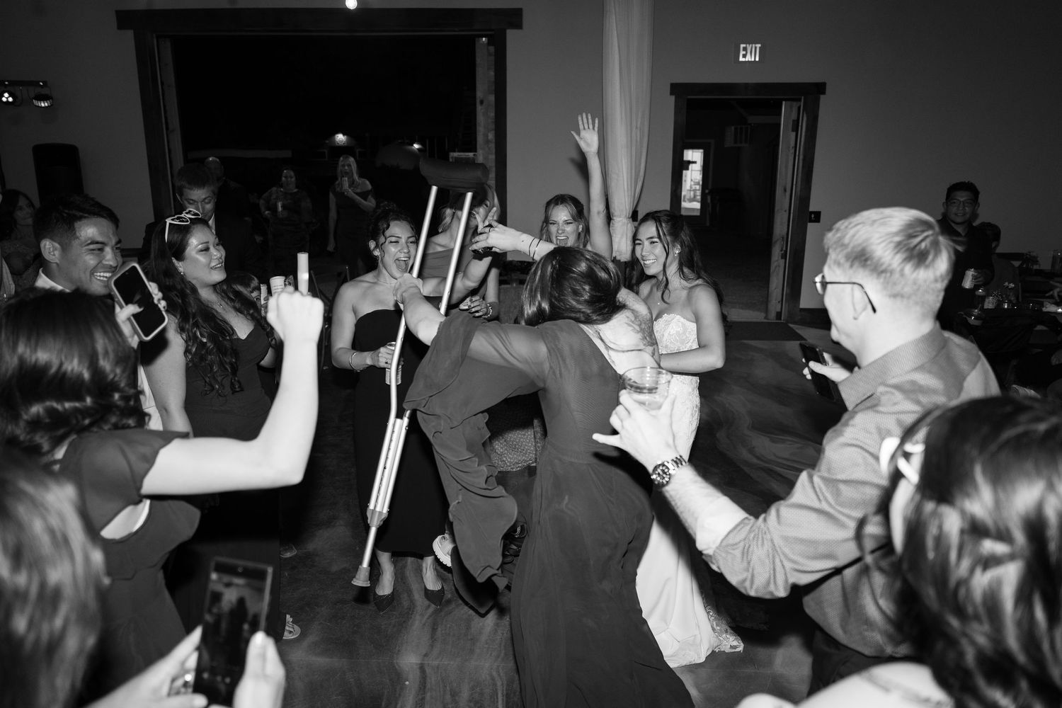 Black and white photo of people dancing with glow sticks at a festive indoor celebration.