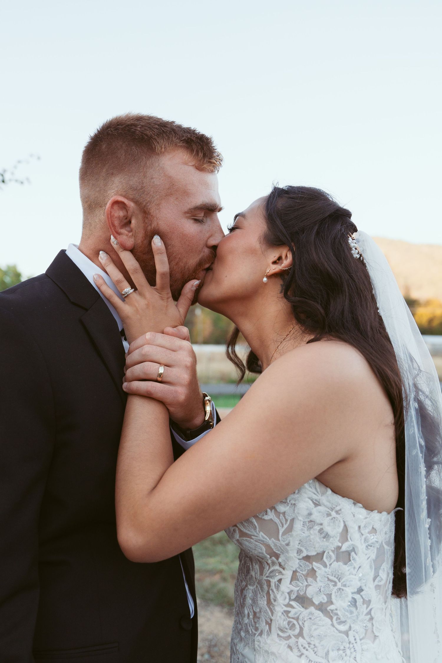 Intimate wedding kiss captured during golden hour with soft natural lighting.