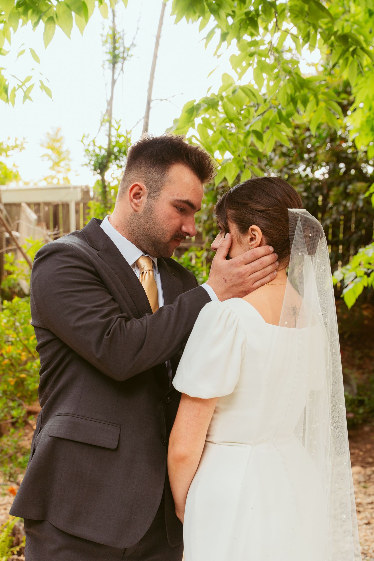 An intimate wedding portrait taken outdoors with green foliage in background.