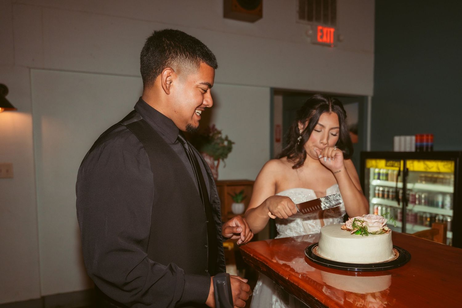 Wedding reception scene showing cake cutting moments in warm ambient lighting.