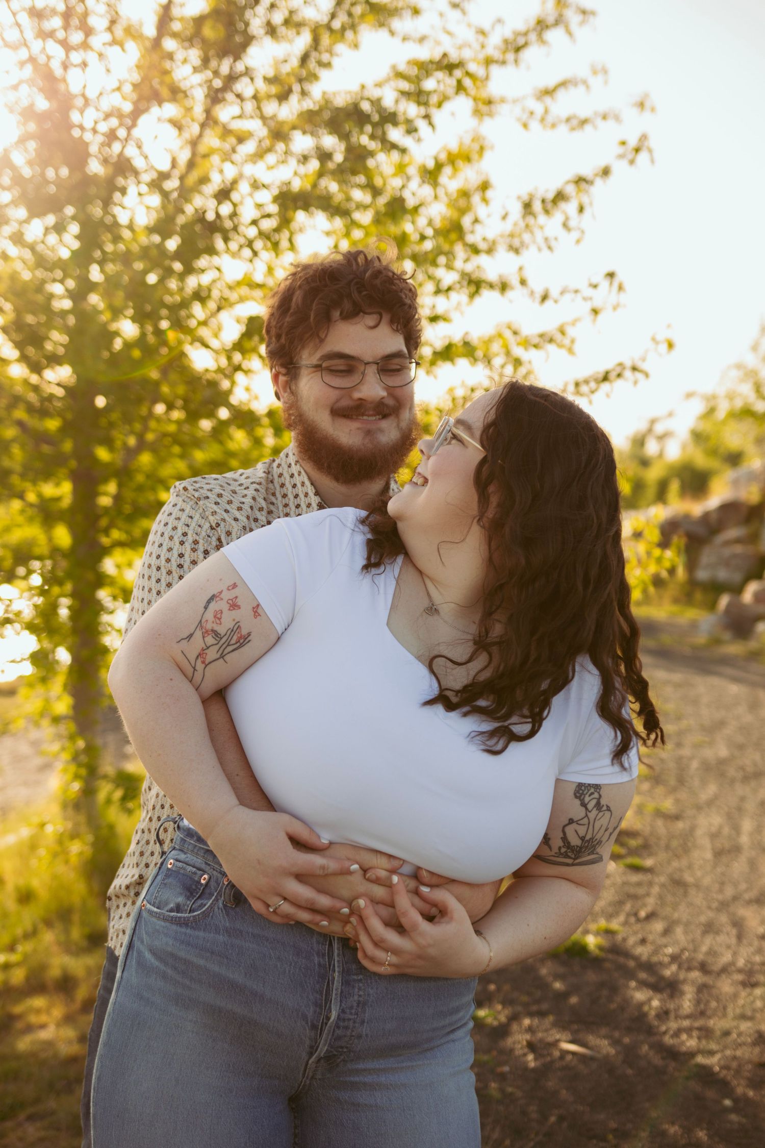 Joyful couple sharing intimate laughs and embraces in warm evening sunlight.