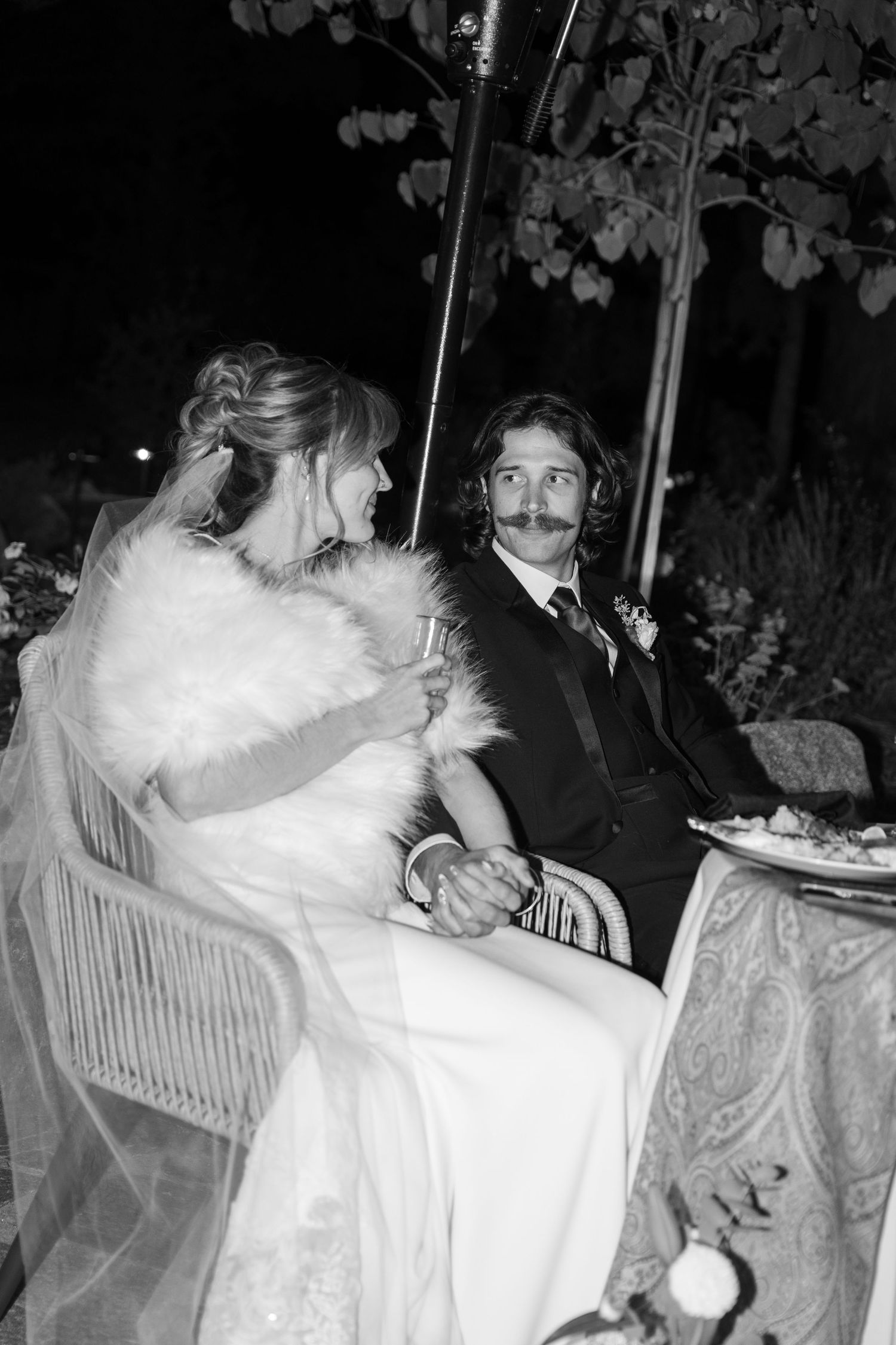 Couple shares tender moment at reception table decorated with elegant white flowers.