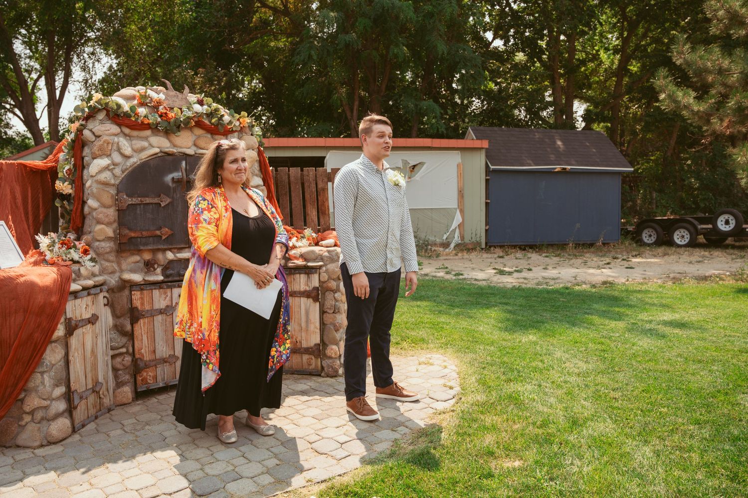 Wide shots of a wedding celebration in a garden setting with stone walls and green landscaping.