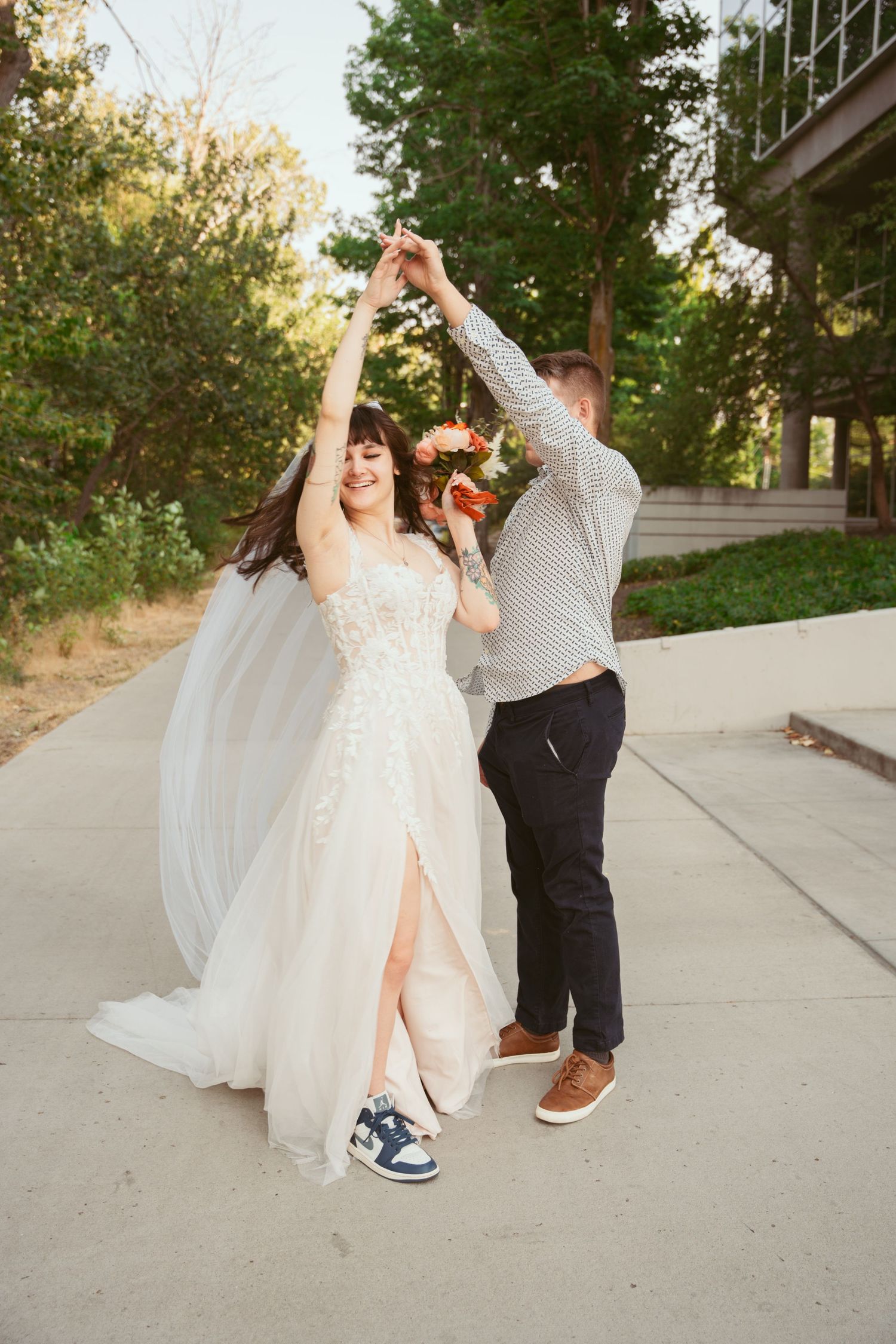 A couple performs a playful dance sequence on a concrete path outdoors.