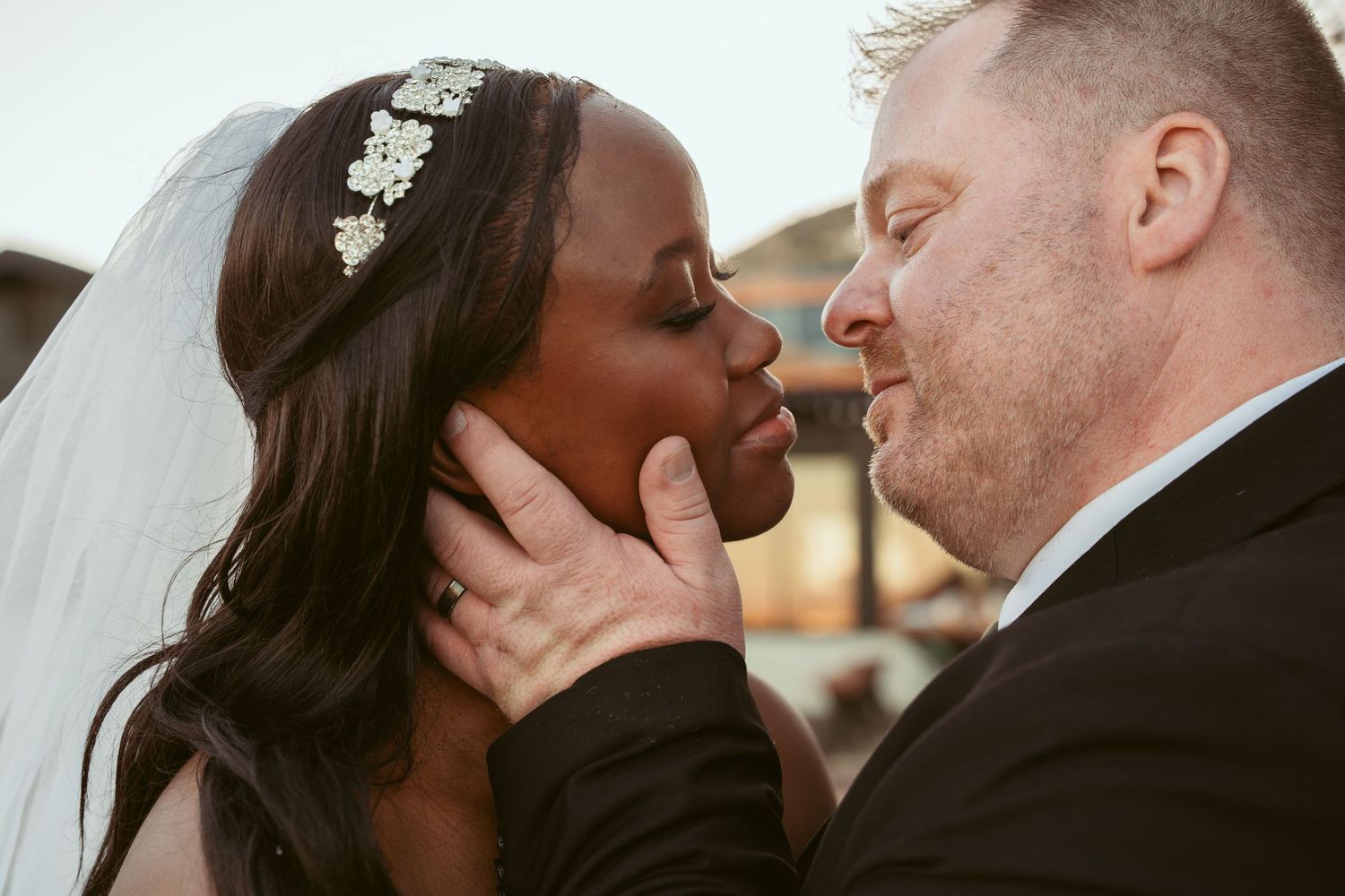 A romantic wedding couple shares an intimate kiss during sunset.