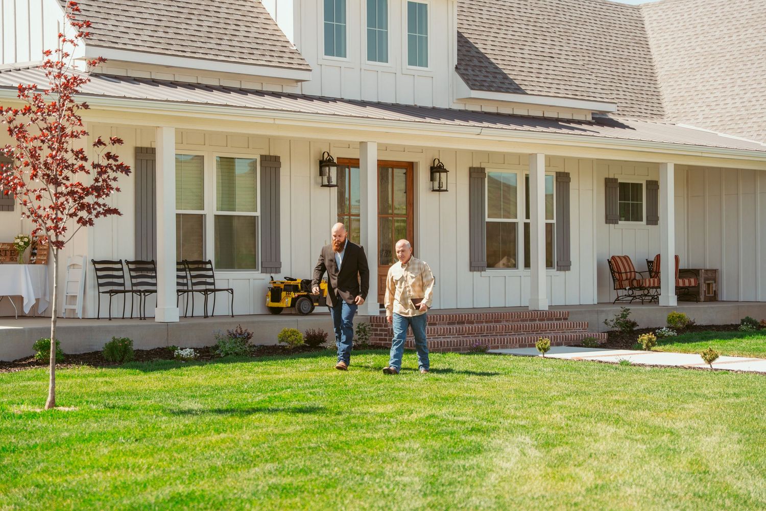 A white modern farmhouse exterior with a covered porch and green lawn.
