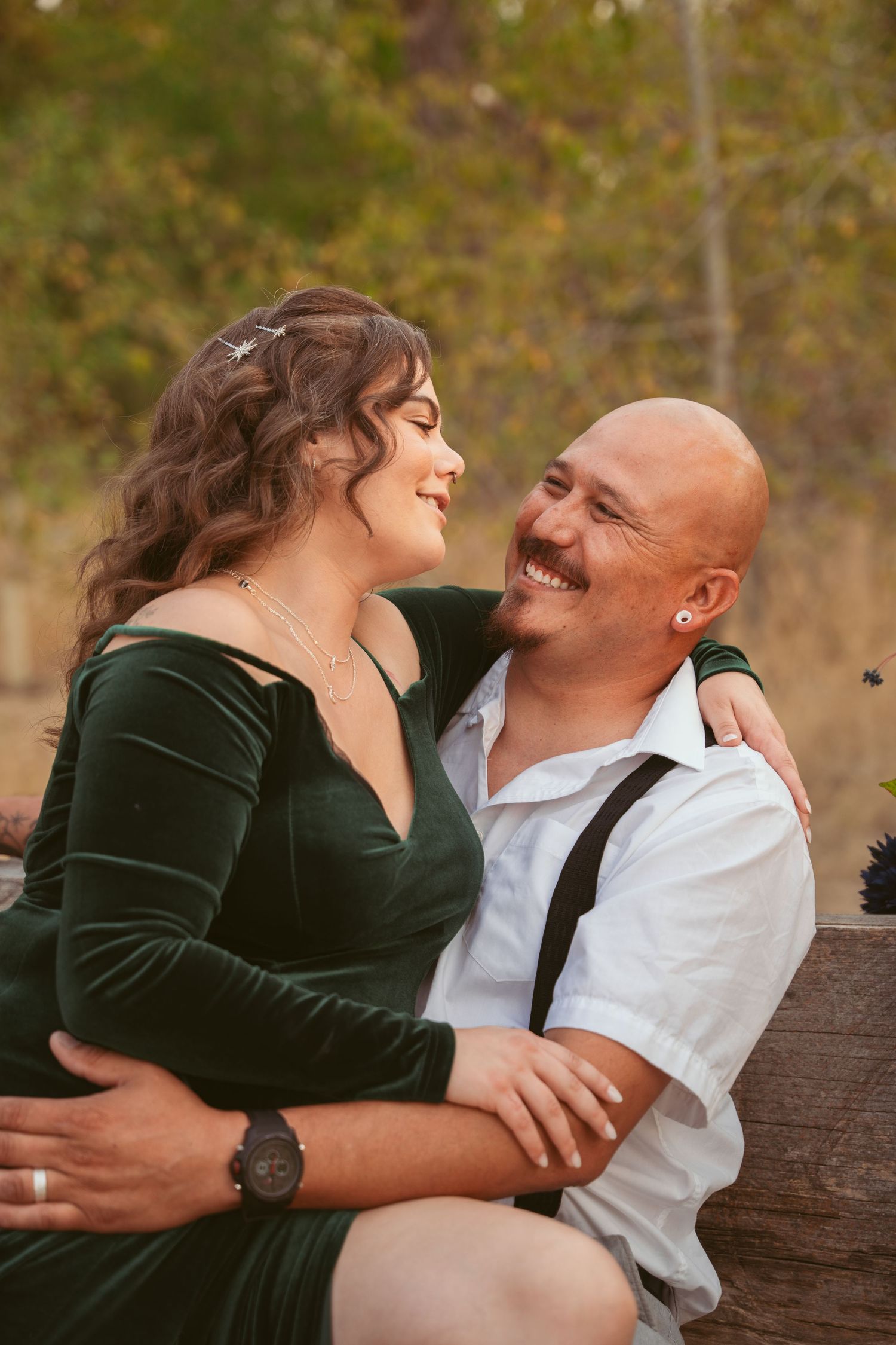 Intimate couple's portrait session on a fallen log with autumn foliage in the background.