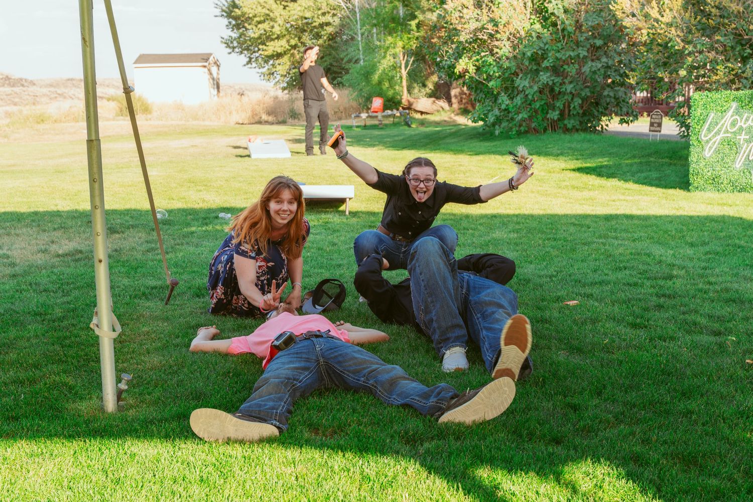 Couple enjoying playful poses on a grassy lawn during an outdoor photo session.