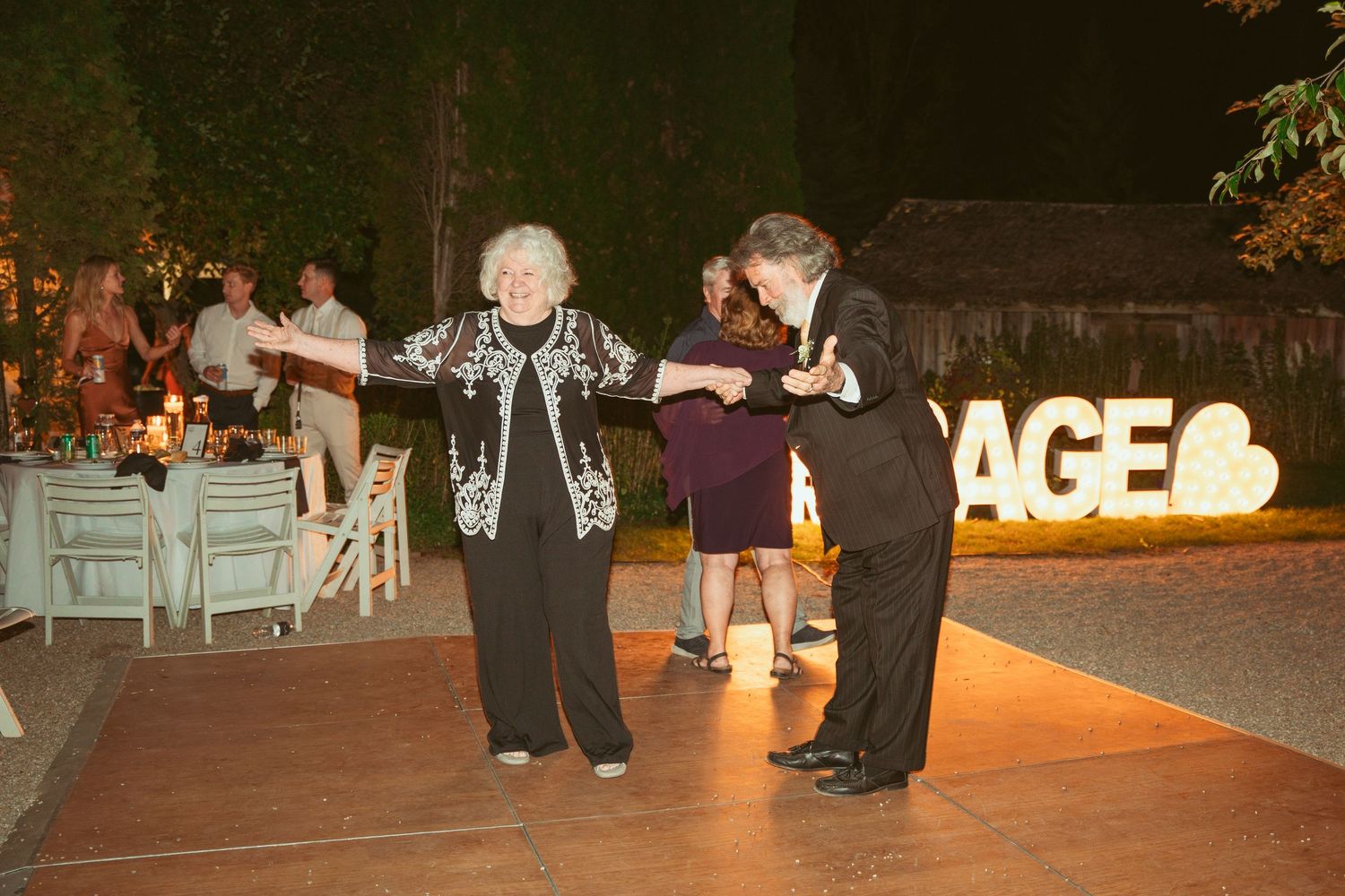 Wedding reception dance floor with glowing signage and guests celebrating.