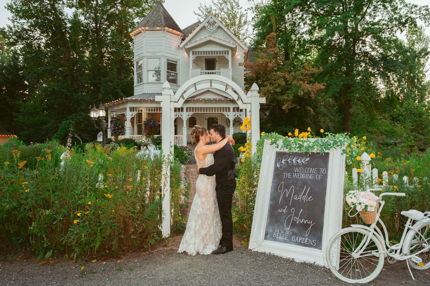 Vintage white house and garden setting decorated for outdoor wedding celebration.