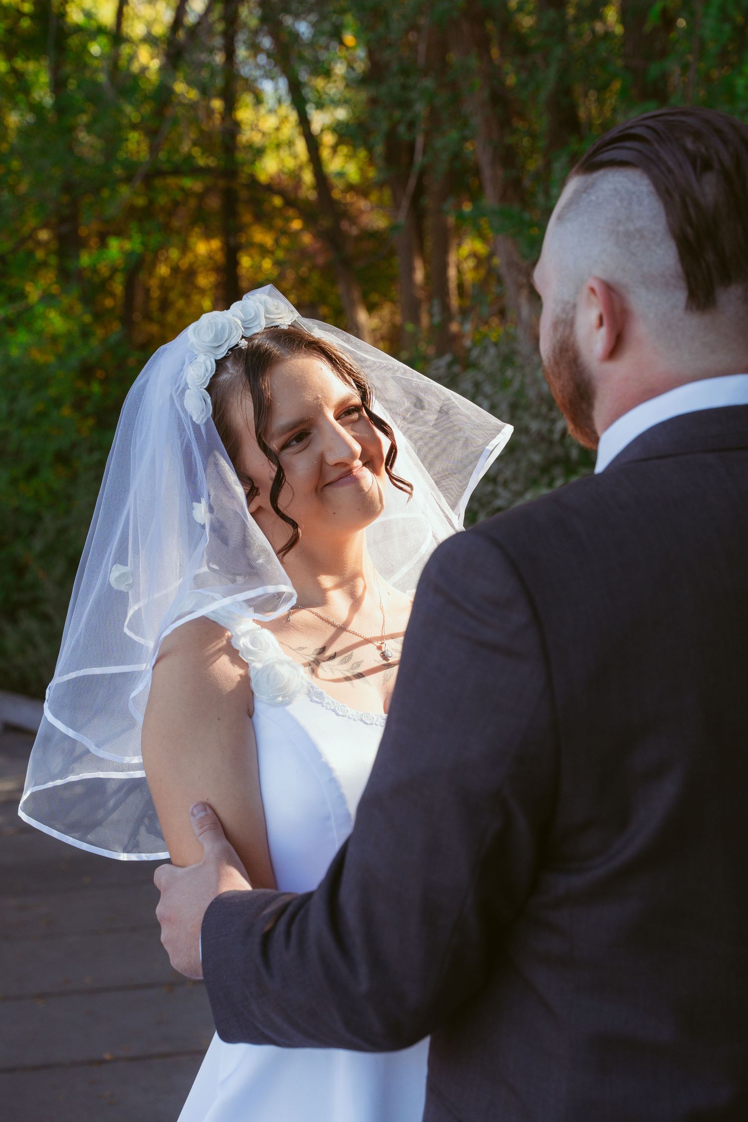 Romantic wedding couple dancing in golden sunlight among trees.