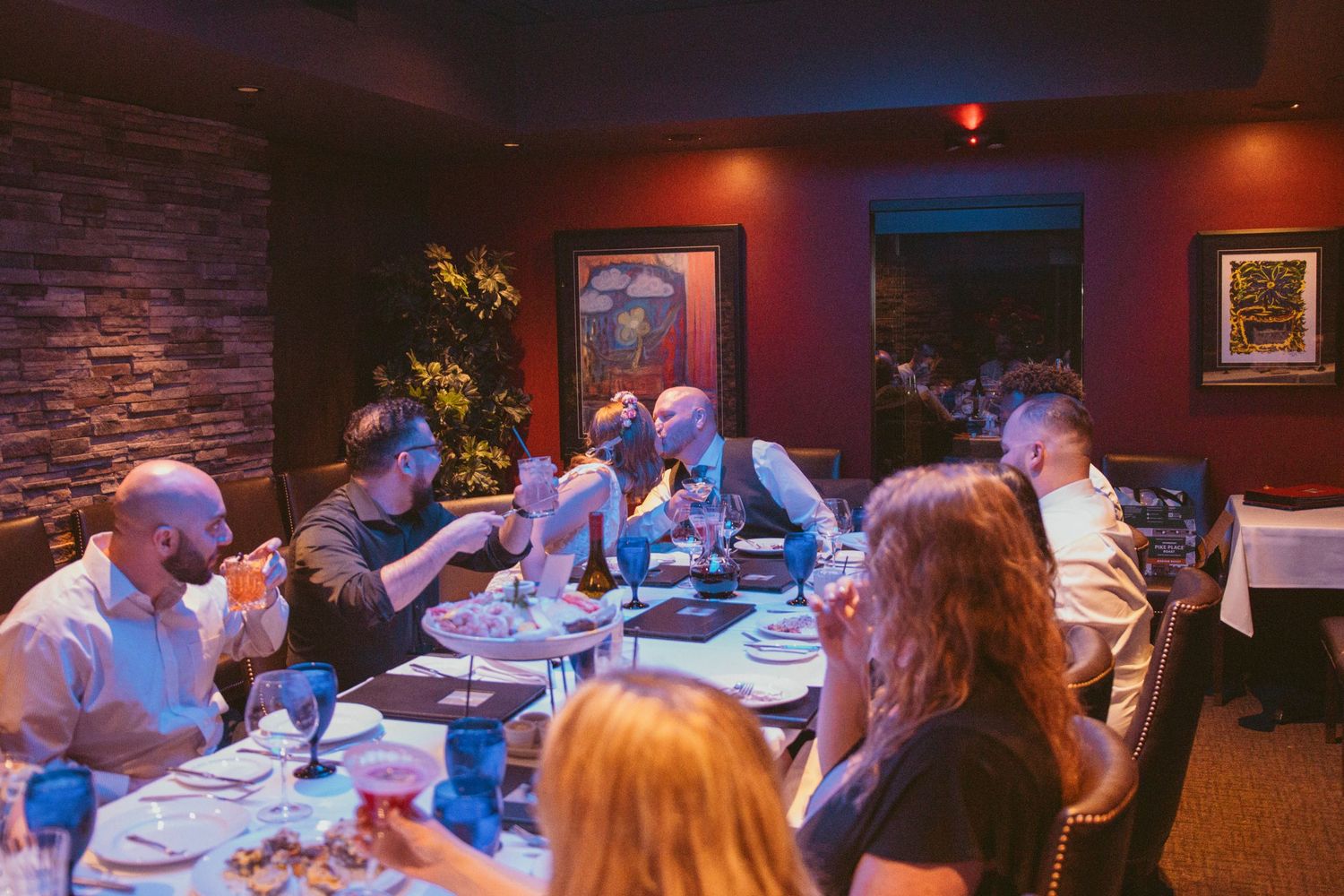 A panoramic view of a dimly lit restaurant dining room with guests seated at multiple tables enjoying their meals.