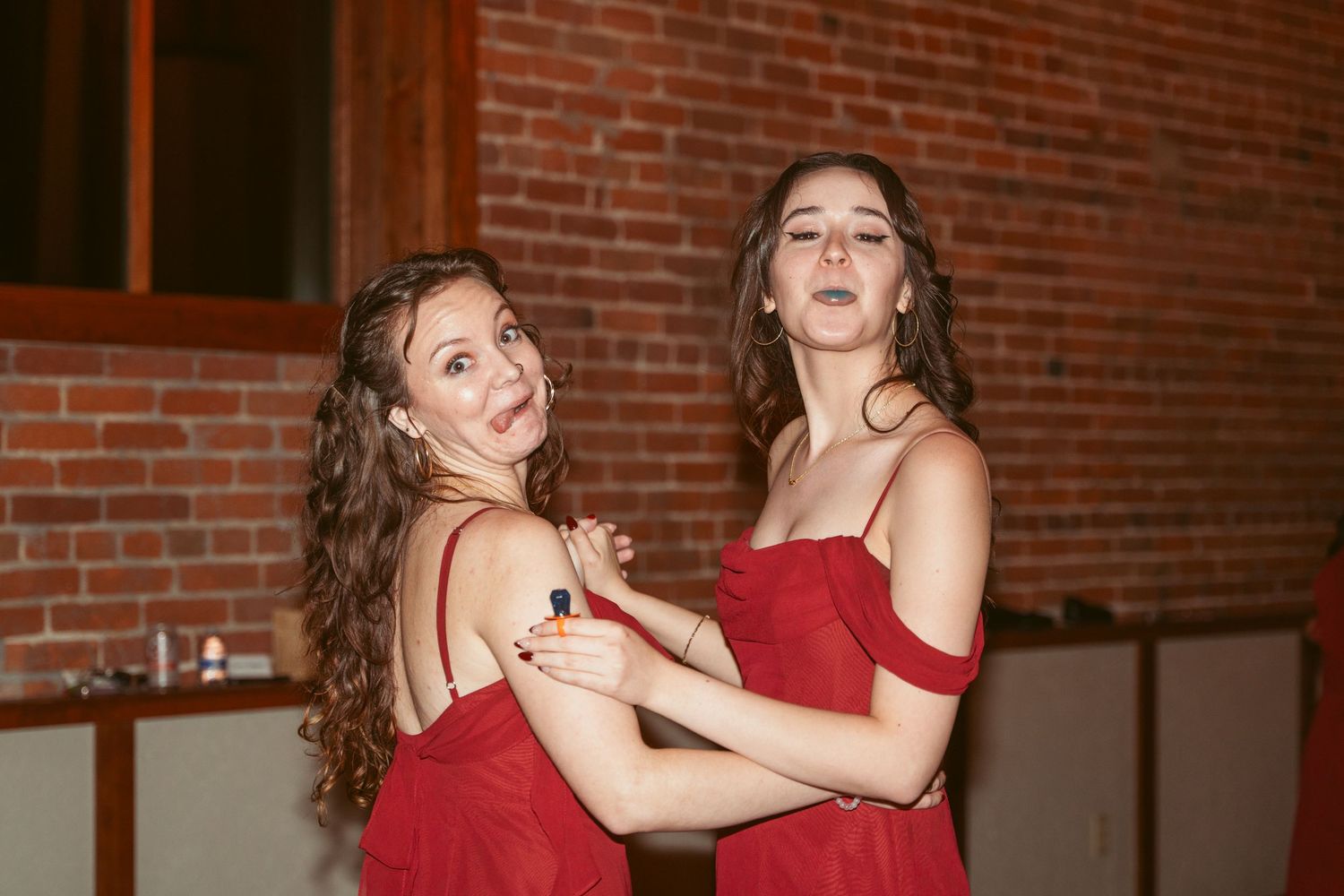 Women in red dresses dancing together at a wedding reception.