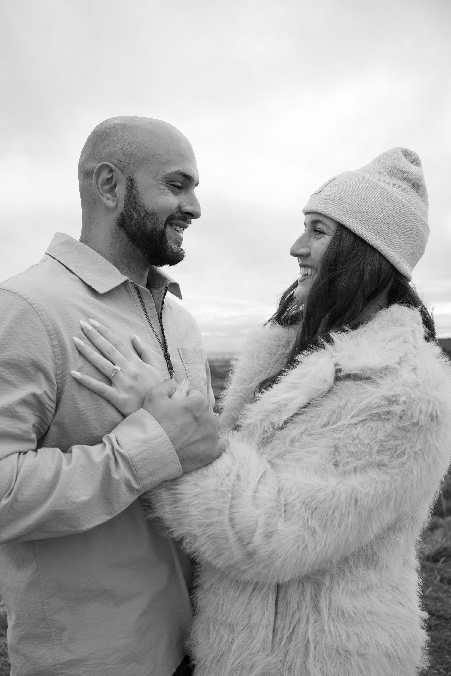 Black and white portrait of a couple in warm winter clothing sharing an intimate moment.