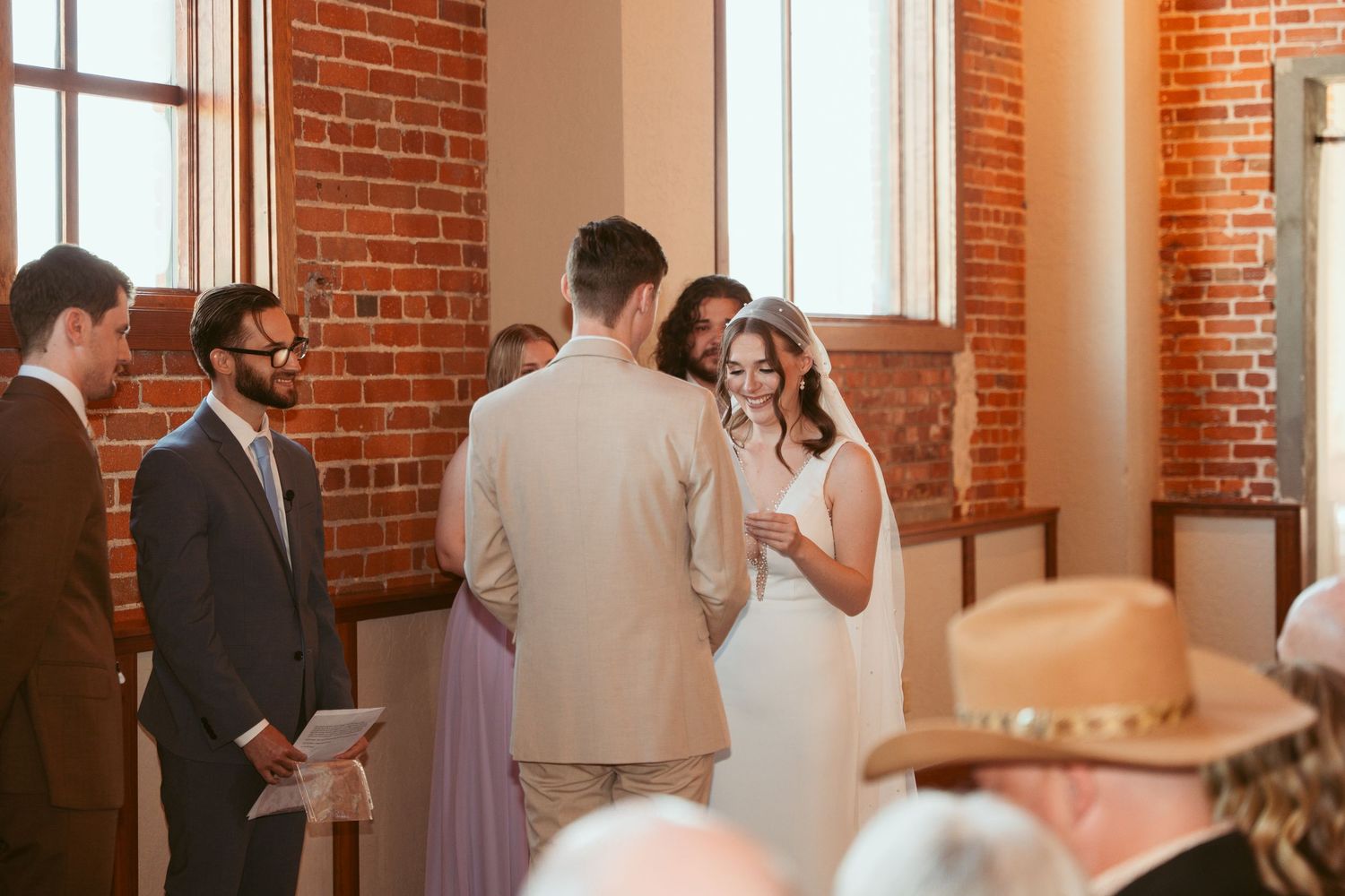 Wedding ceremony proceedings in an elegant brick-walled event space.