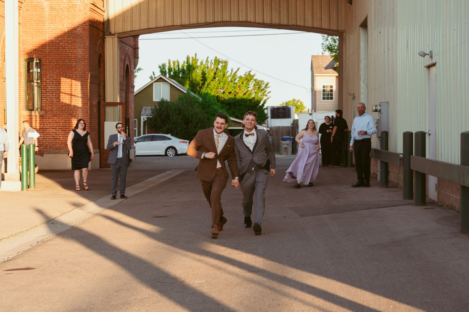 Wedding party walks along a covered outdoor walkway during sunset.