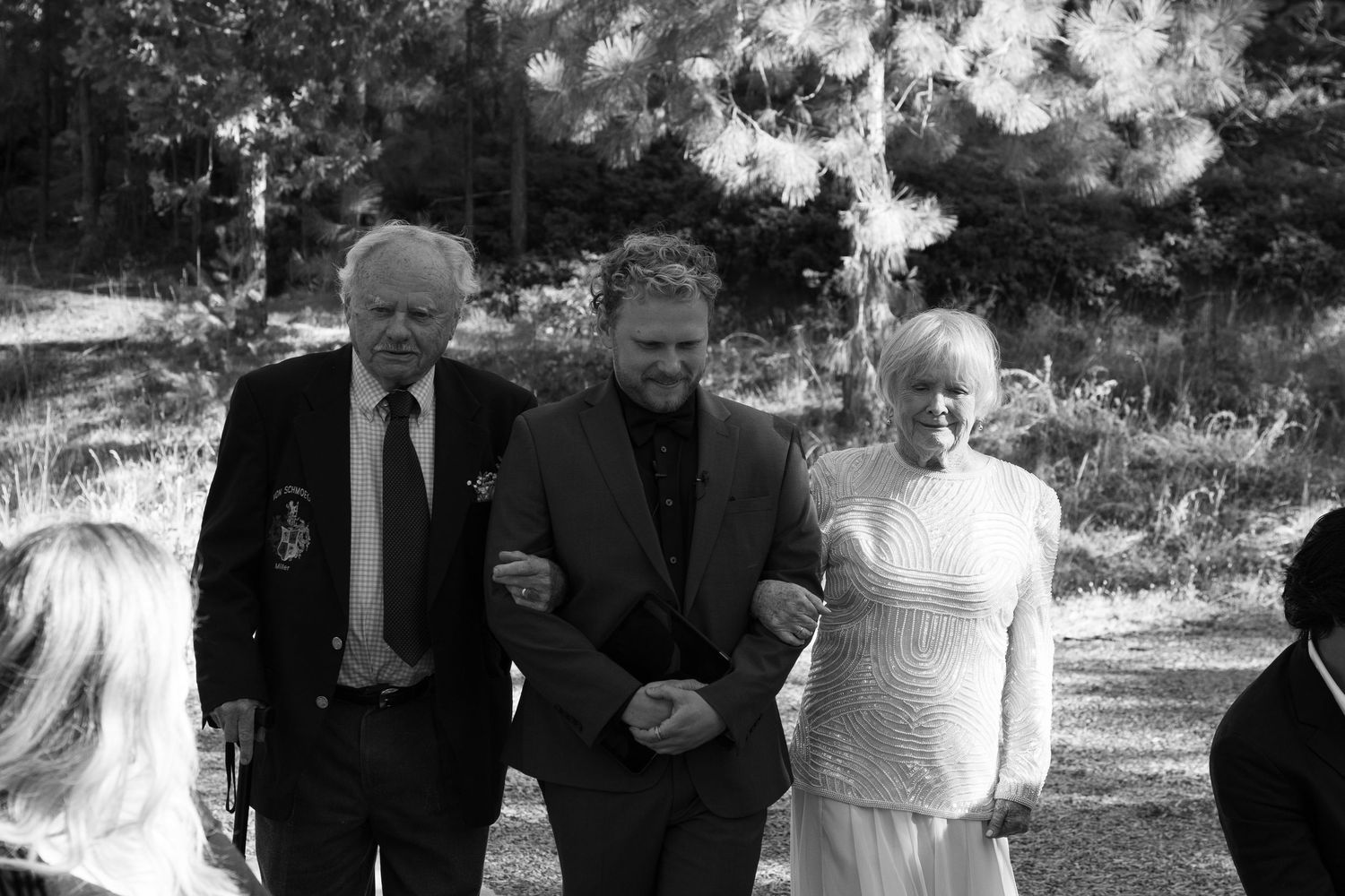 Black and white photo of wedding guests seated outdoors during ceremony.