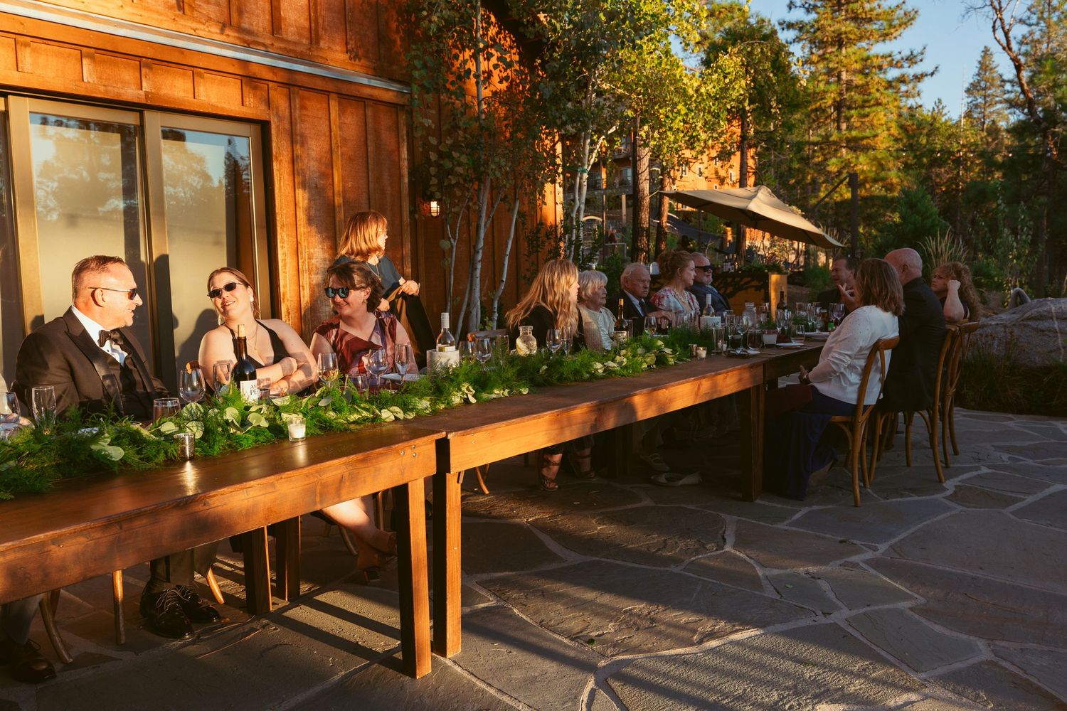 Outdoor wedding reception venue with wooden benches and ambient lighting at dusk.
