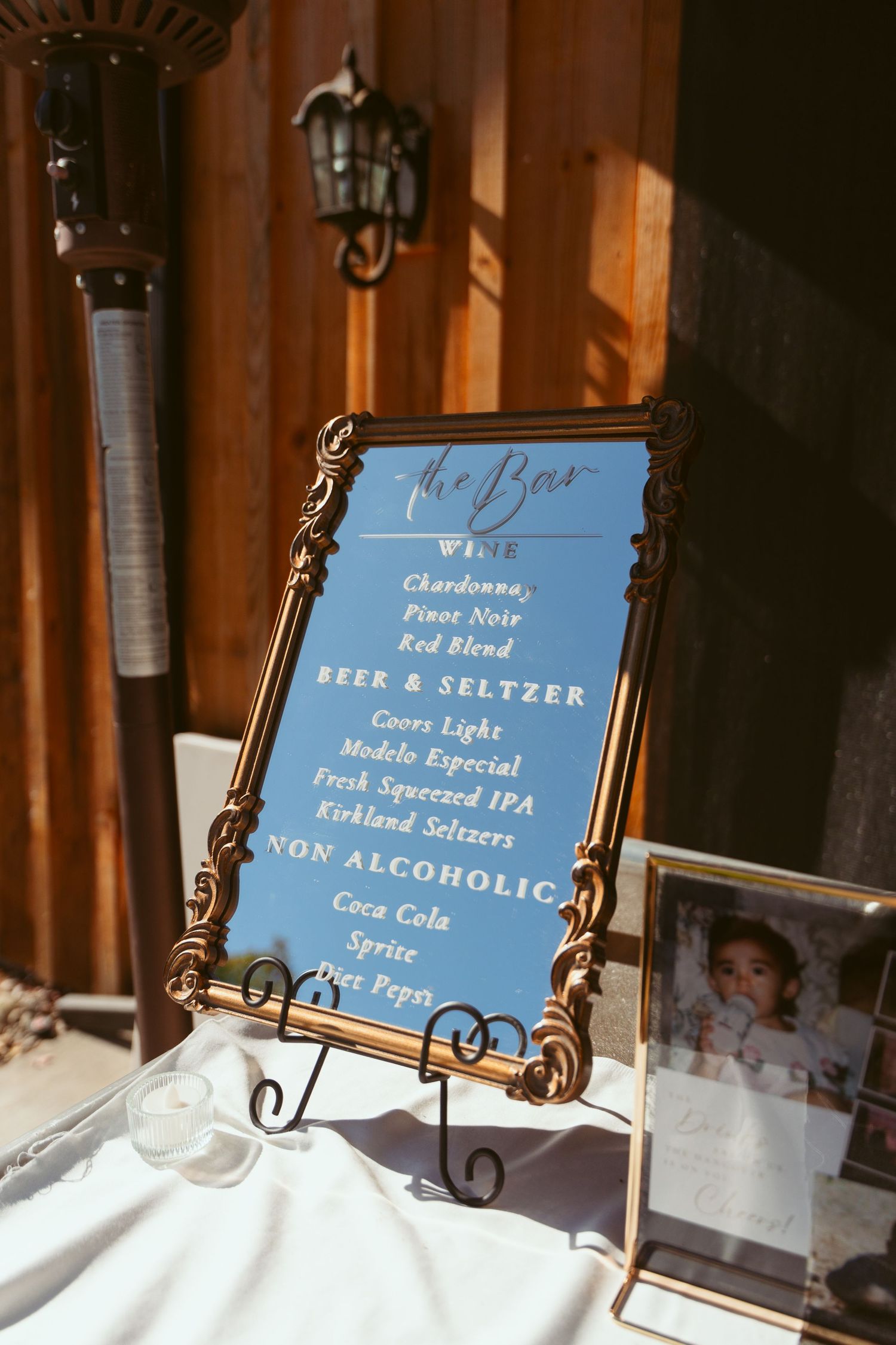 Wedding bar menu displayed in ornate frame with drink options listed.