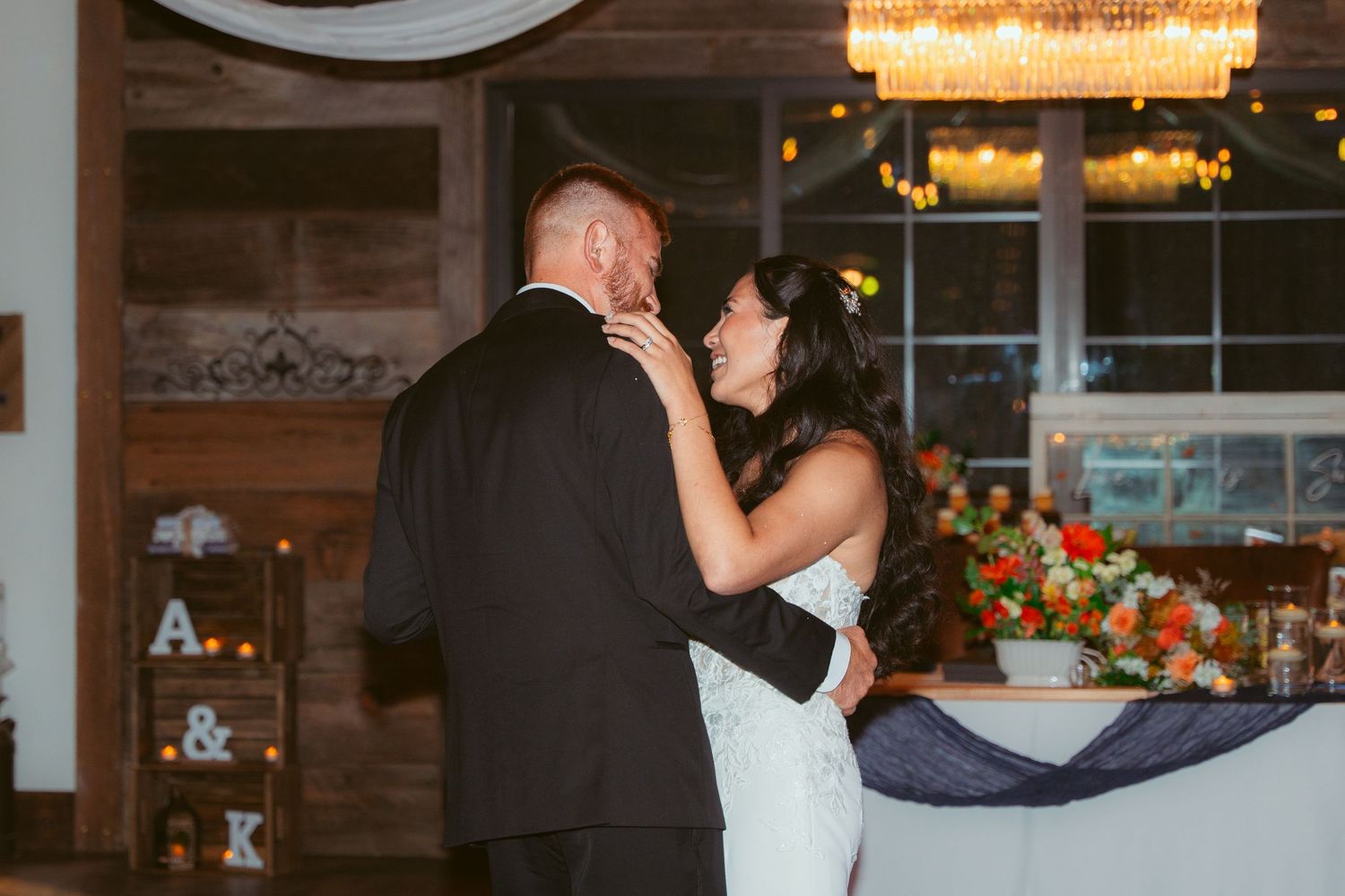 Wedding reception space features rustic wood walls and elegant lighting fixtures.