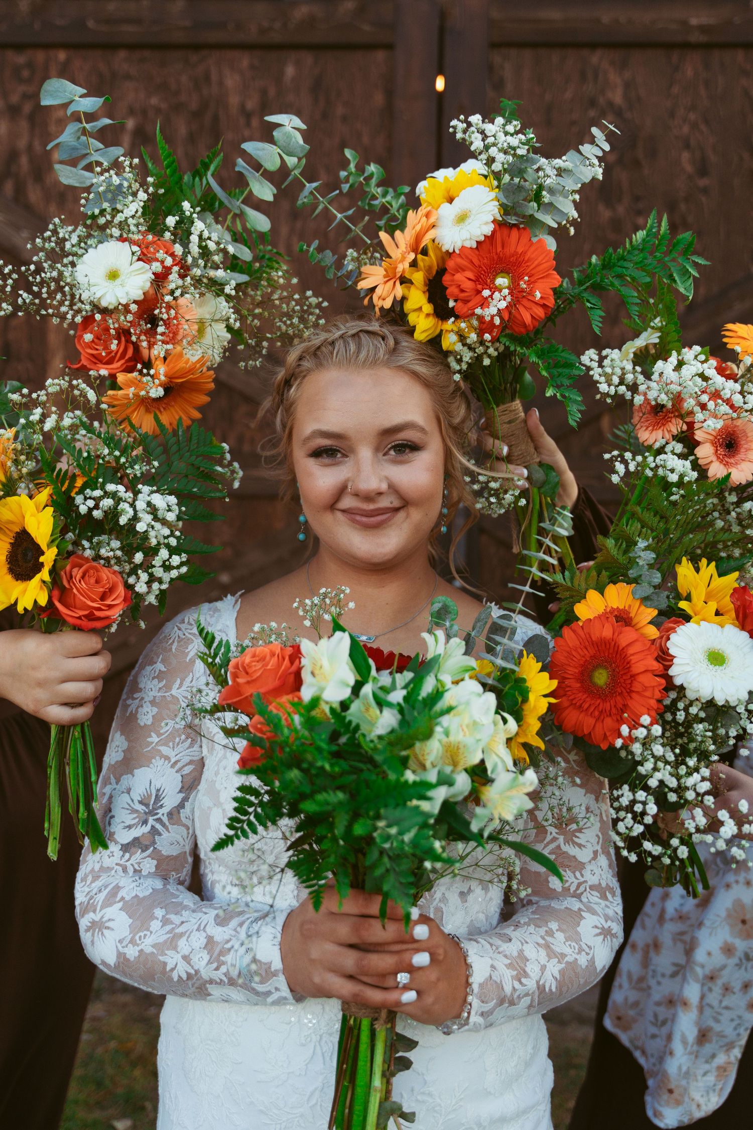 Vibrant bridal bouquet featuring sunflowers, orange gerberas, and eucalyptus against rustic wooden backdrop.