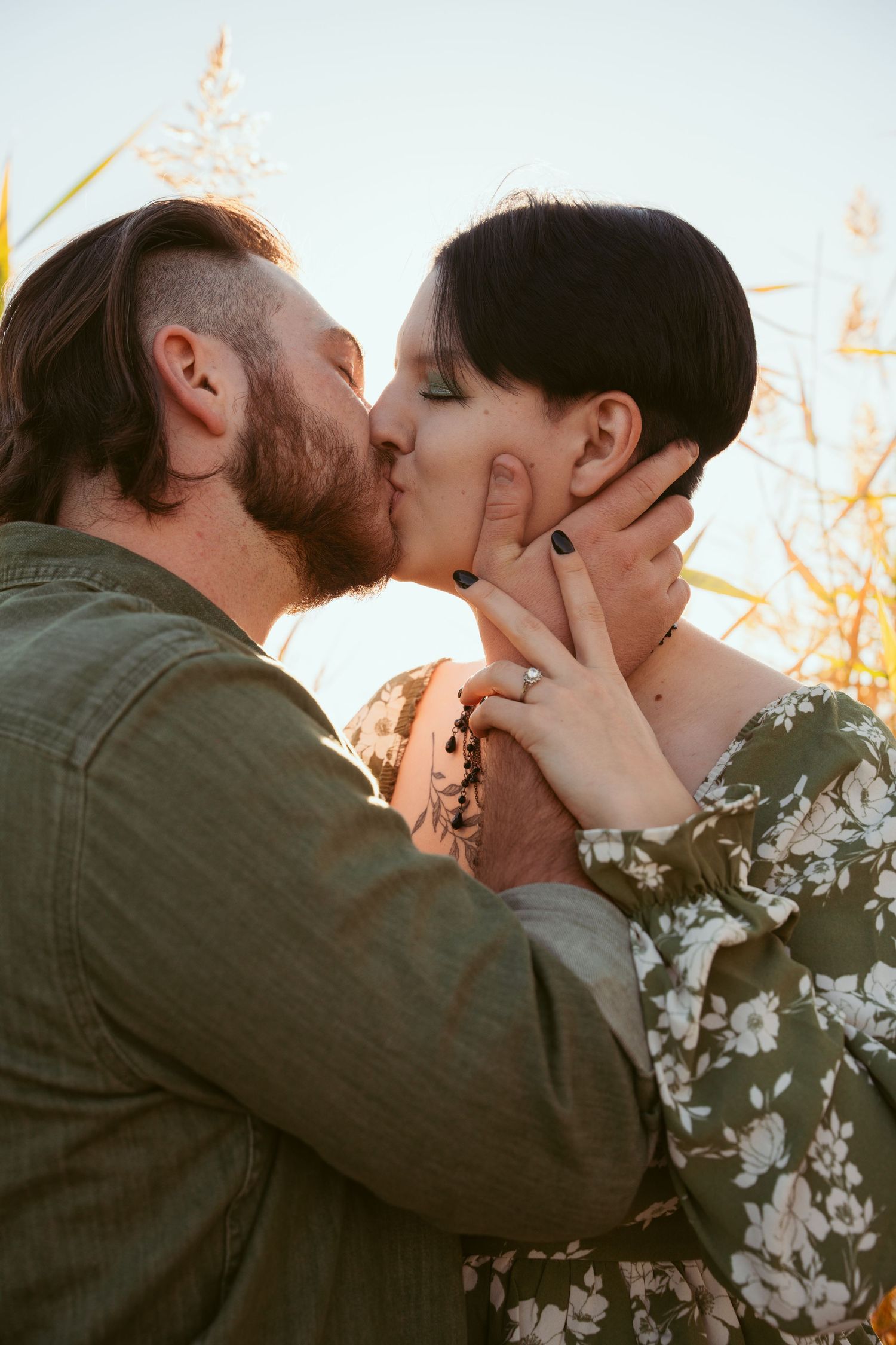 Romantic sunset kiss between couple with one in denim jacket and other in floral print.