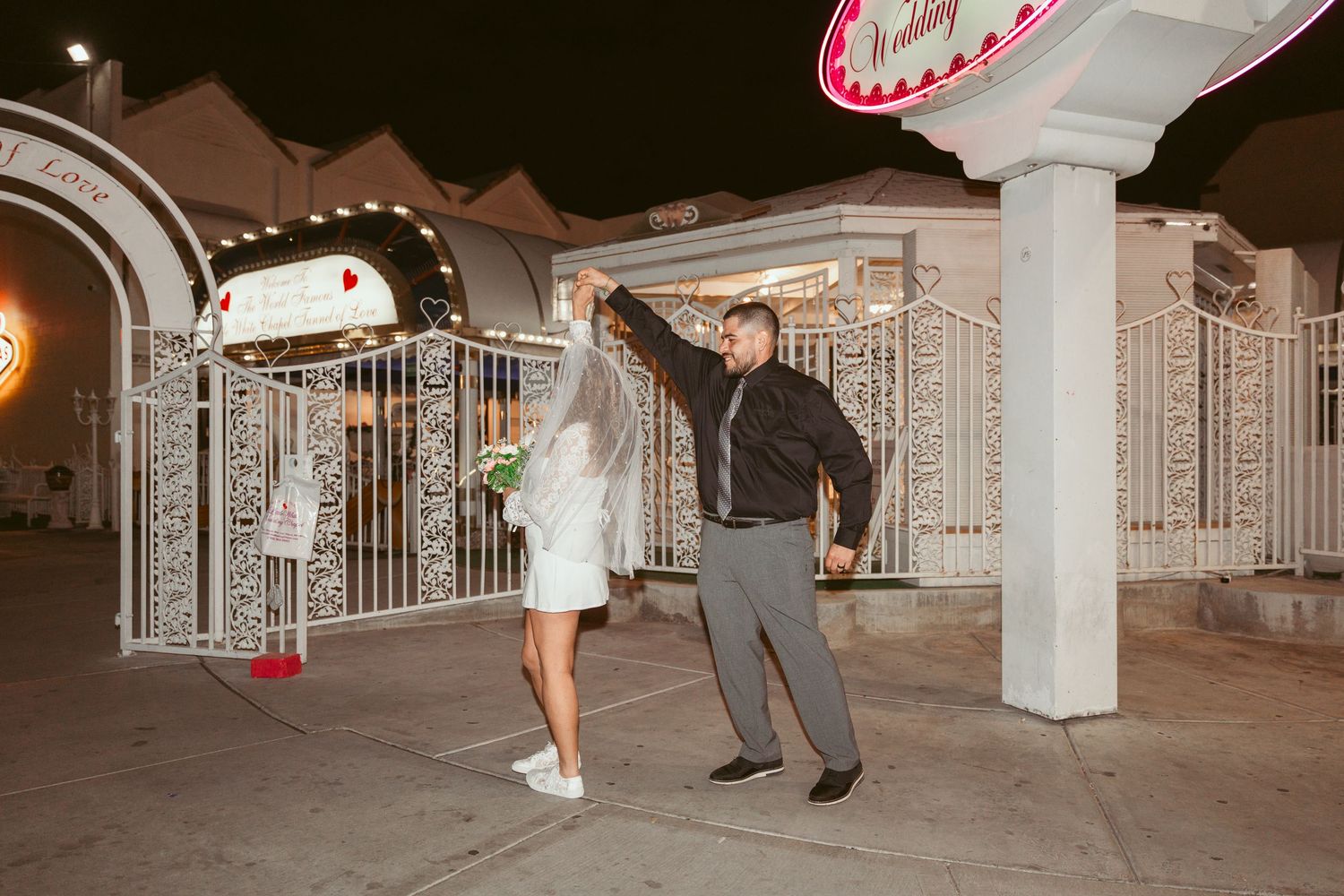 Couple dancing at night under white architectural columns with decorative details.
