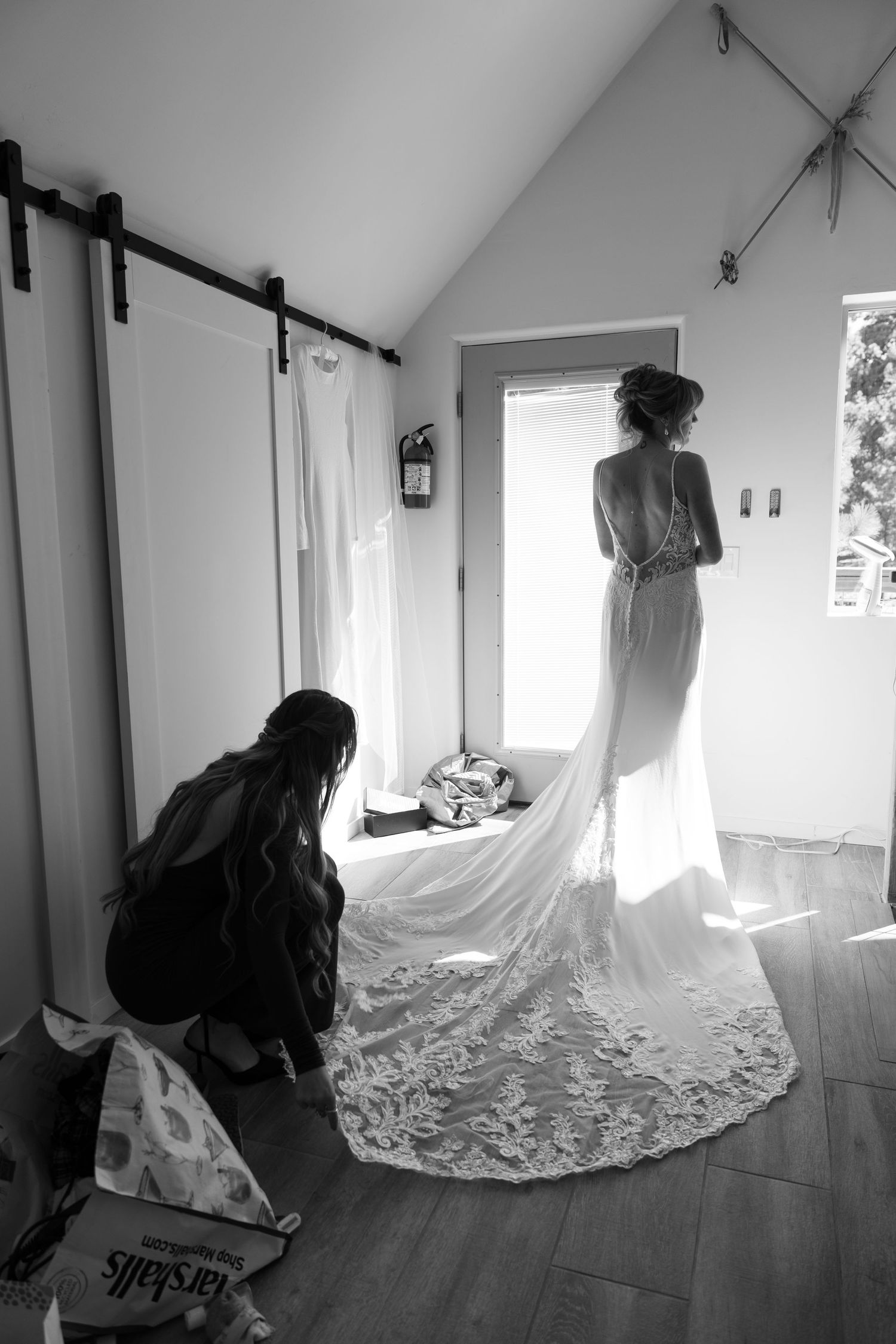 Black and white photo of bride in flowing wedding gown with dramatic train.