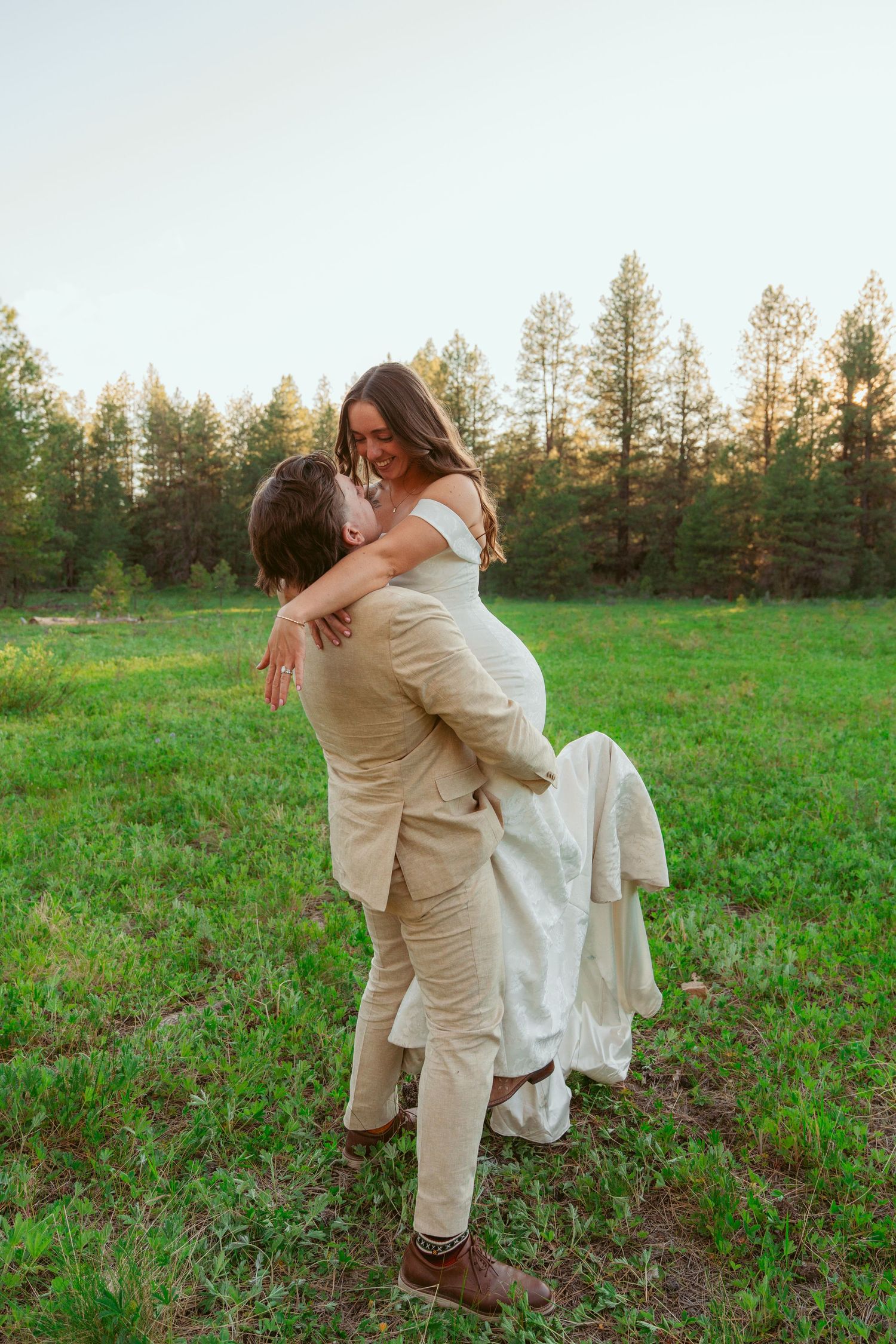 Joyful couple embracing and spinning in a meadow during sunset.