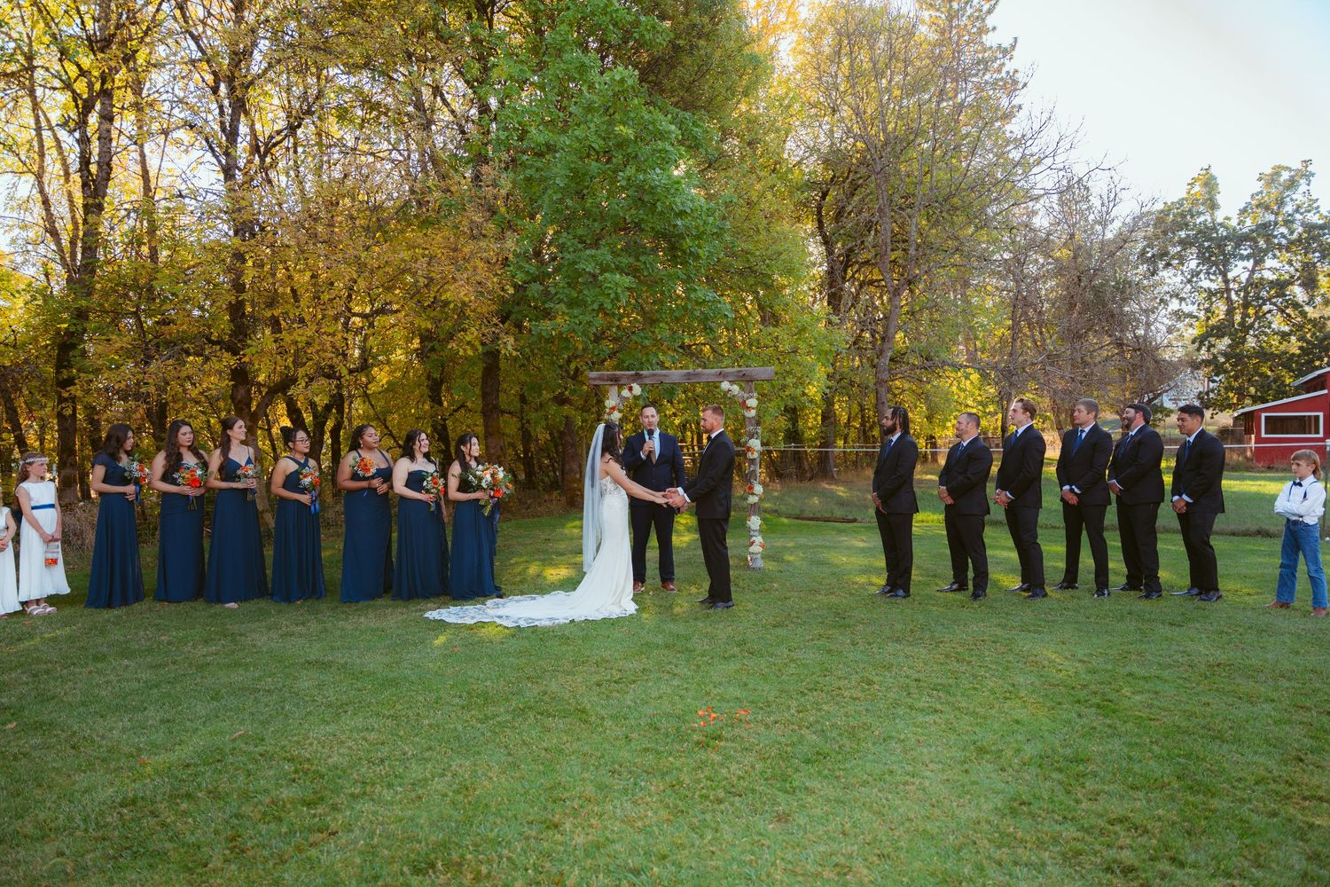 Wedding party gathered on lawn during golden autumn afternoon.