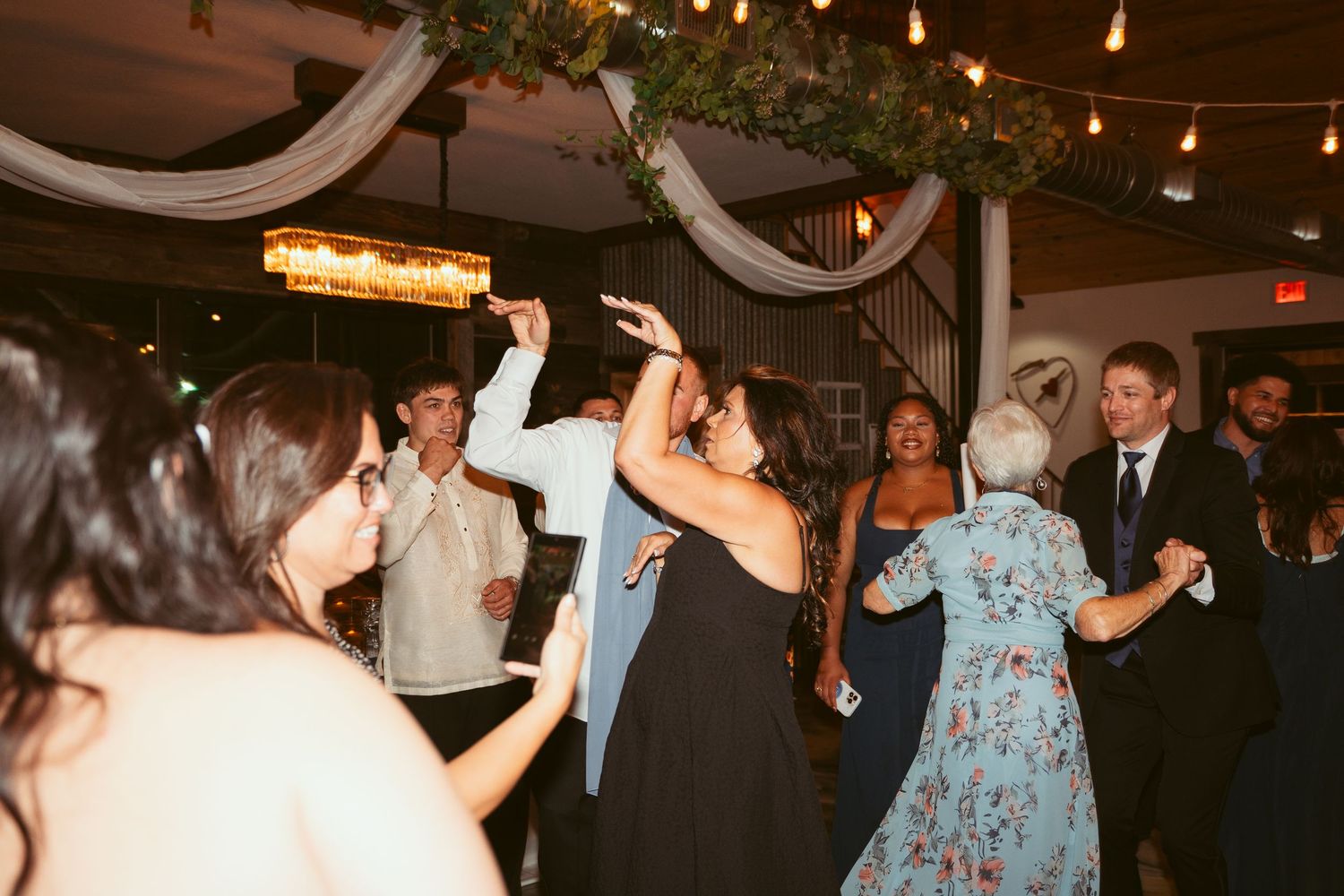 Partygoers enjoying themselves on a crowded dance floor under warm ambient lighting.