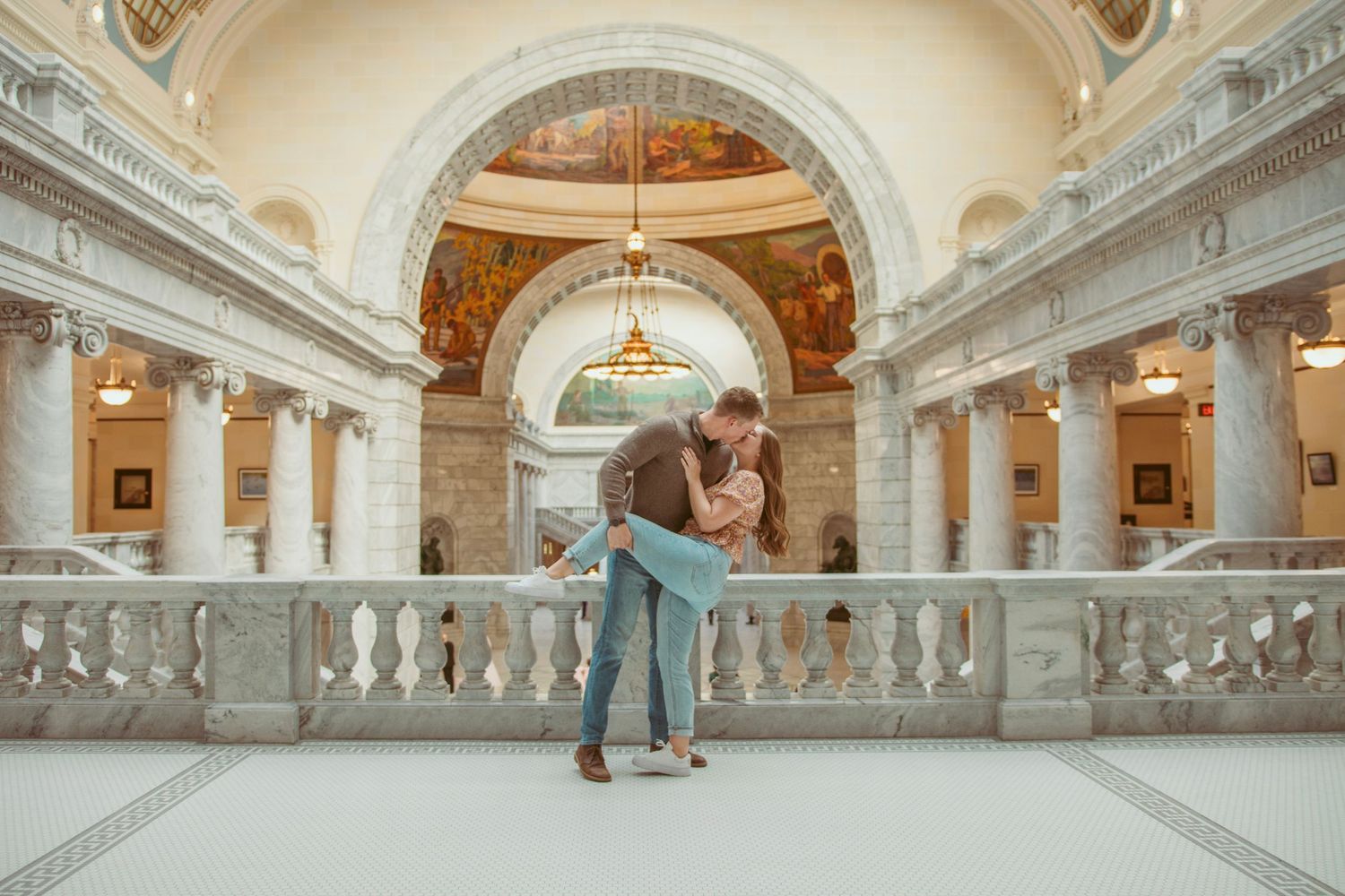 Romantic moment captured under ornate classical architecture with grand columns and arches.