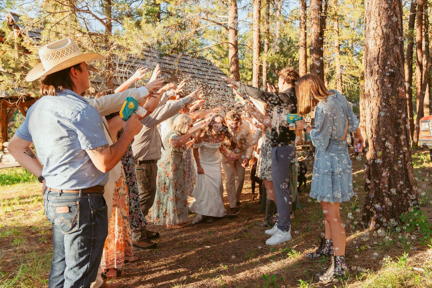 Wedding celebration unfolds in a natural outdoor setting surrounded by towering pine trees.