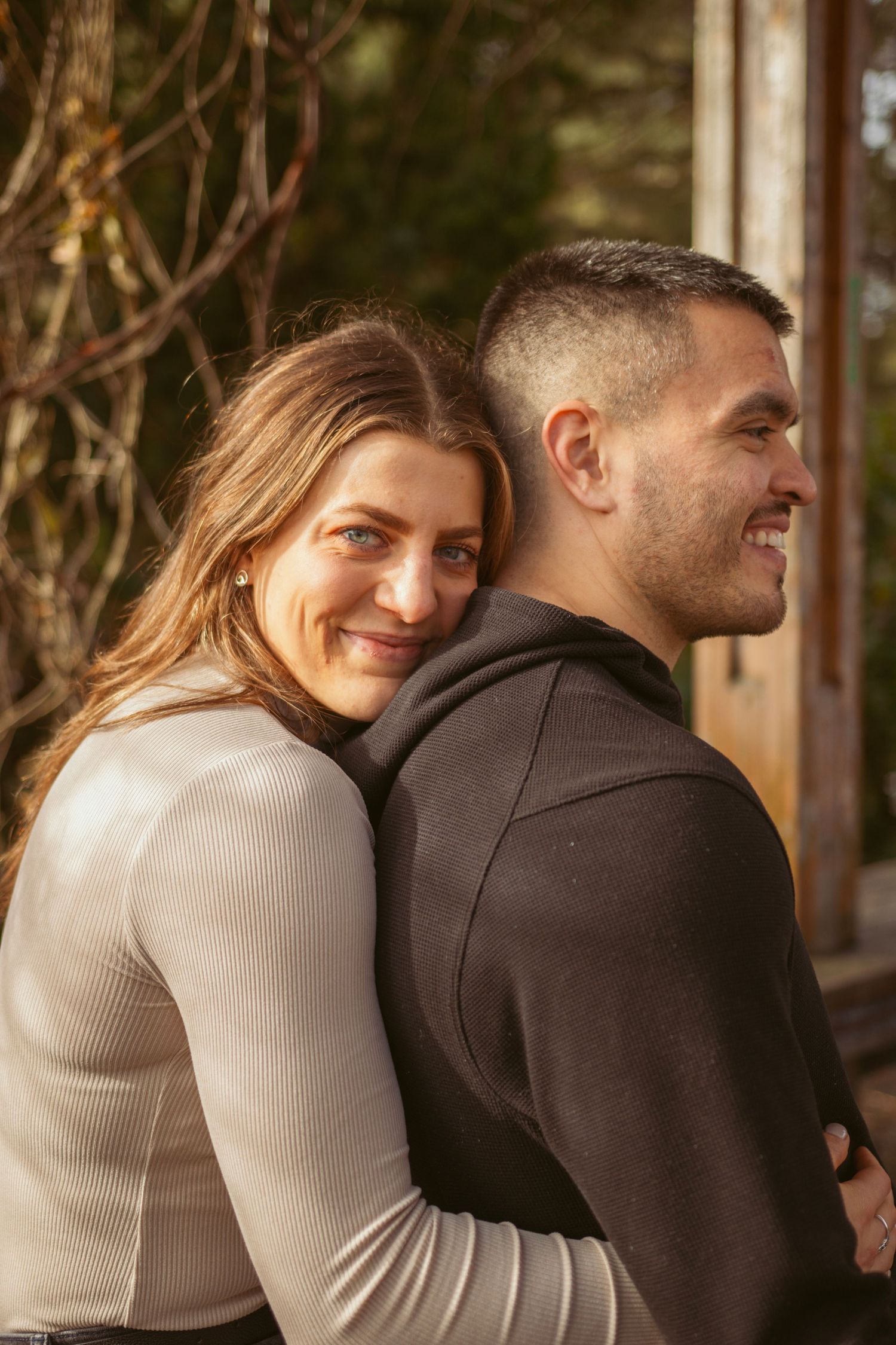 A couple in casual attire sharing warm embraces during an outdoor photo session.