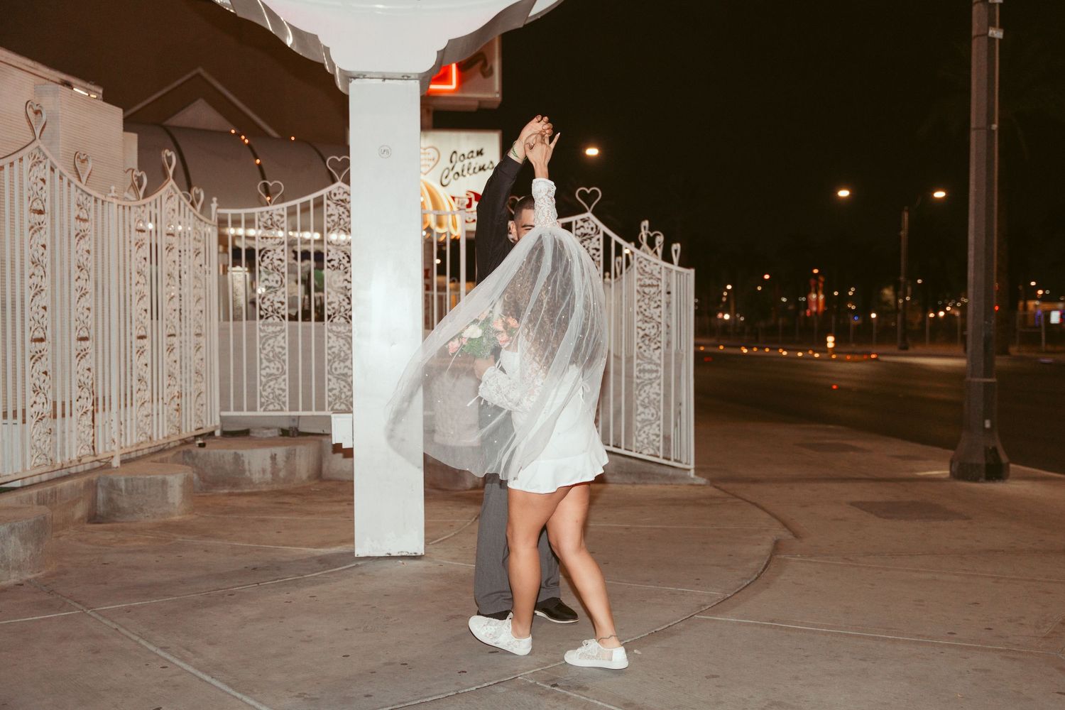 Couple dancing at night under decorative white columns and architectural details.