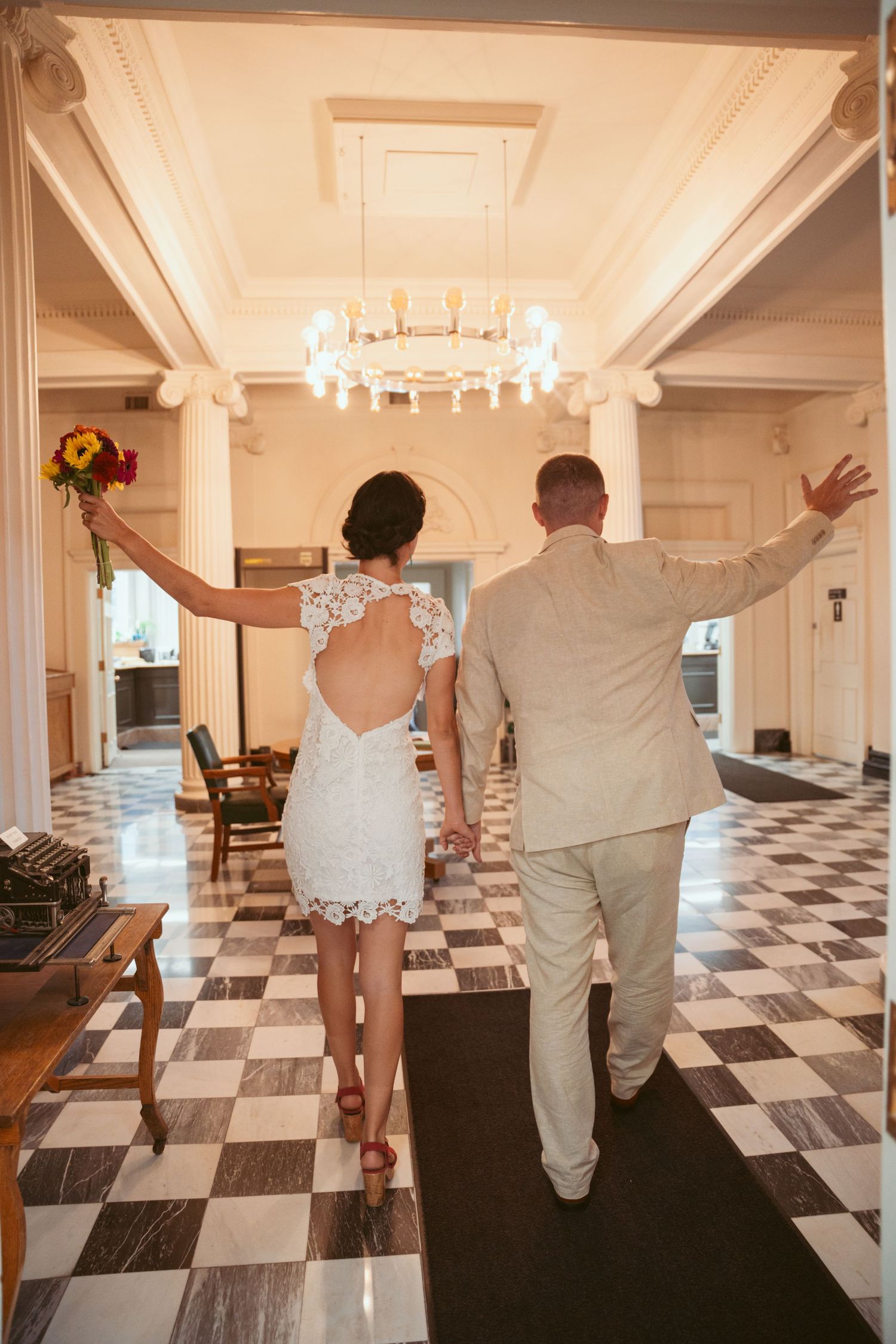 A couple celebrates on a black and white checkered floor in an elegant venue.